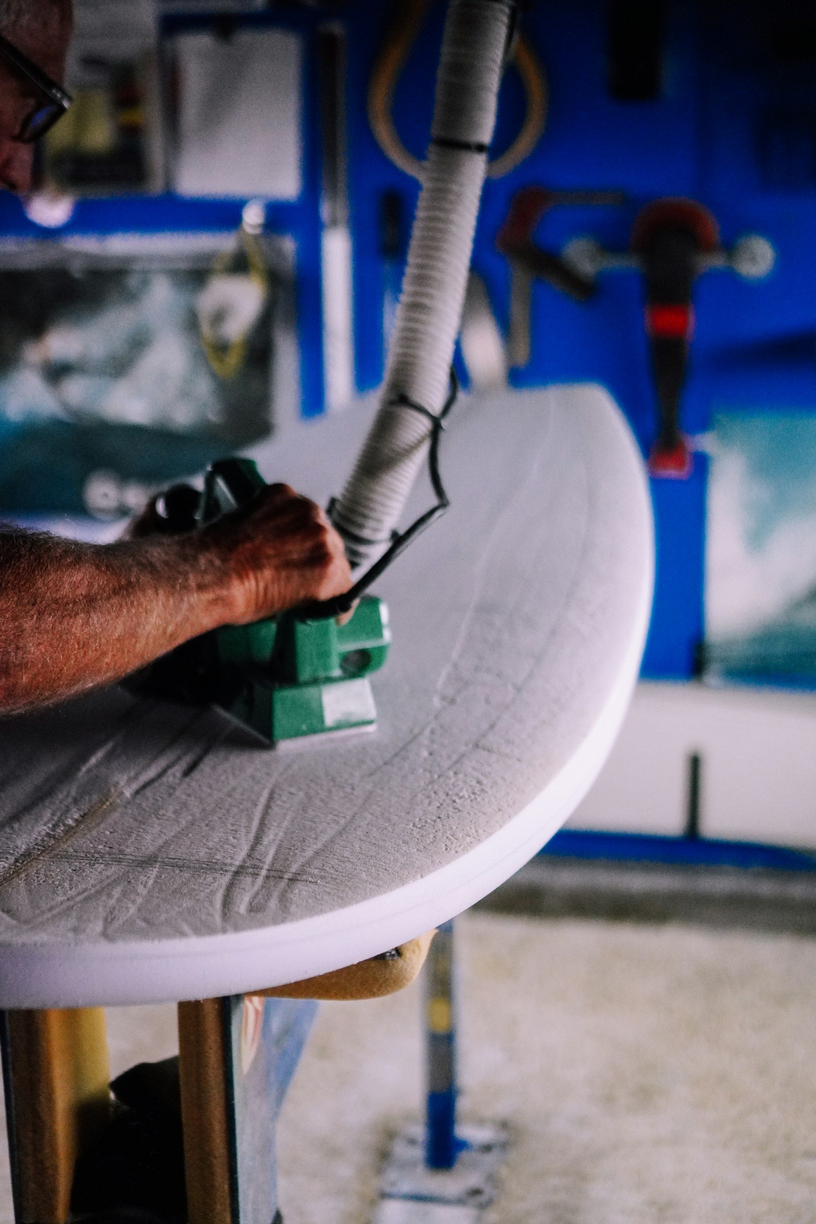 A person operating a large industrial machine with a circular metal surface, likely in a manufacturing or workshop setting.
