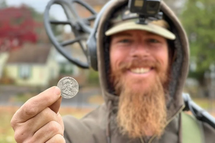 Rich VanWinkle from Quarter Hoarder holding a Ben Franklin silver half dollar found metal detecting at an early 1800s home