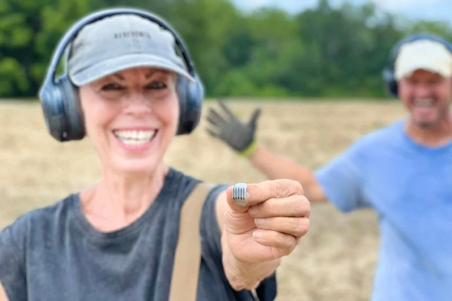 Lynne and Matt from Quarter Hoarder holding a sterling silver ring with an opal stone that was found metal detecting in a colonial farm field