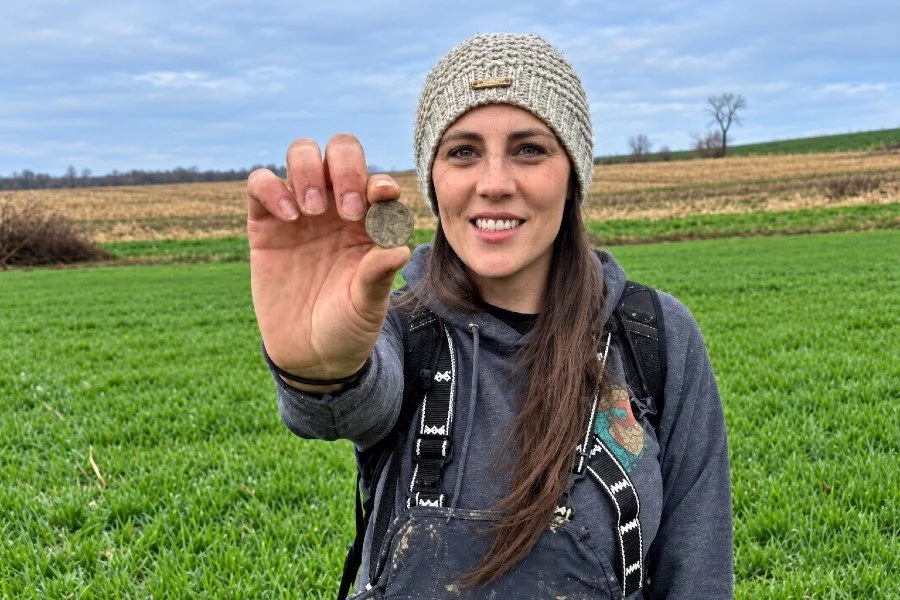 Bre the Metal BREtectorist from Quarter Hoarder posing with an old coin she found metal detecting in a farm field