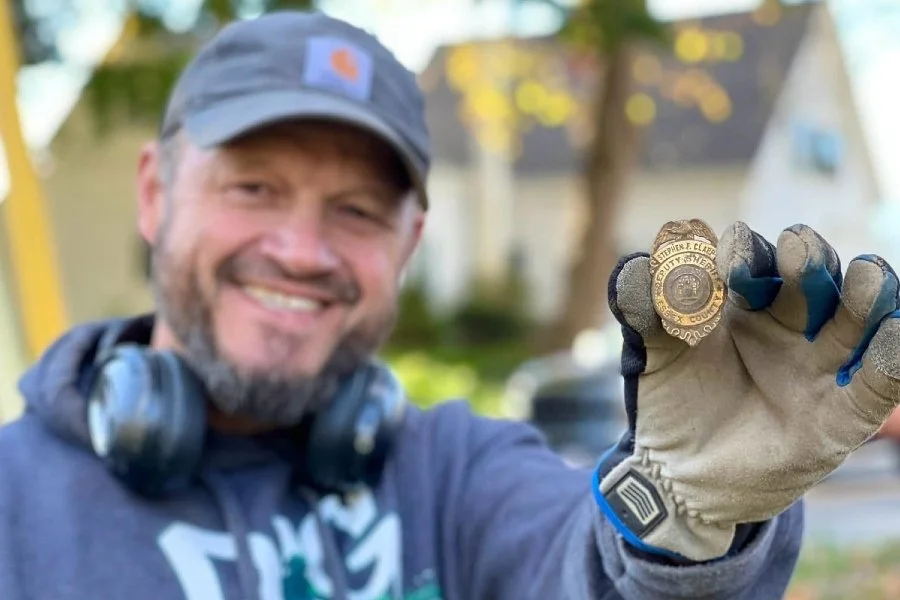 Matt from Quarter Hoarder posing with a 1970's police badge he found metal detecting in MA
