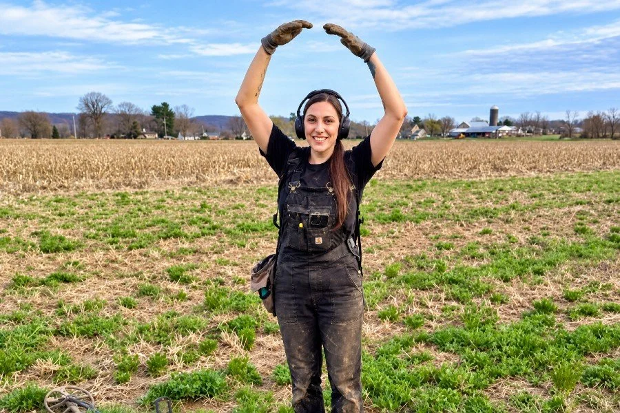 Bre the Metal BREtectorist from Quarter Hoarder giving the large copper sign in a field indicating she just found an old US large cent while metal detecting in a field