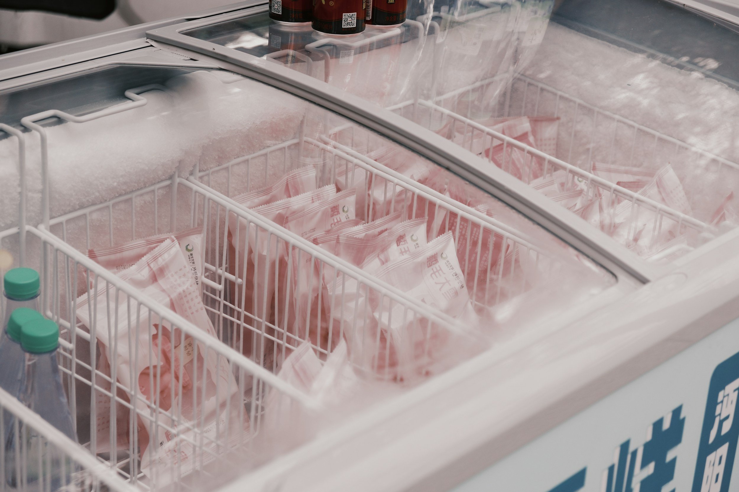 Open freezer with packaged ice packs and bottles inside.