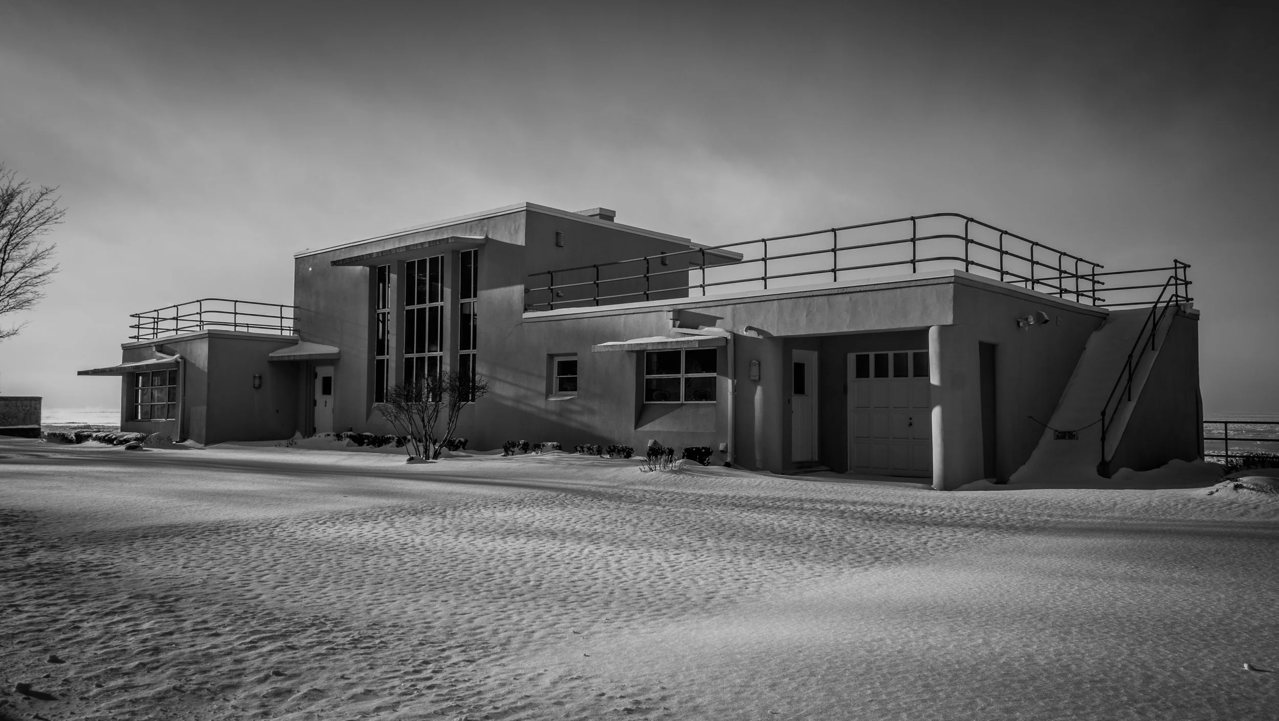A modern house on a snow-covered landscape with a clear sky in the background.