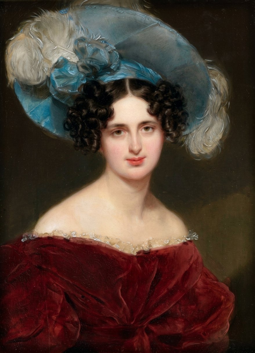 A portrait of a young woman with dark curly hair, wearing a large blue hat with feather details, and a red off-shoulder dress with a beaded neckline.