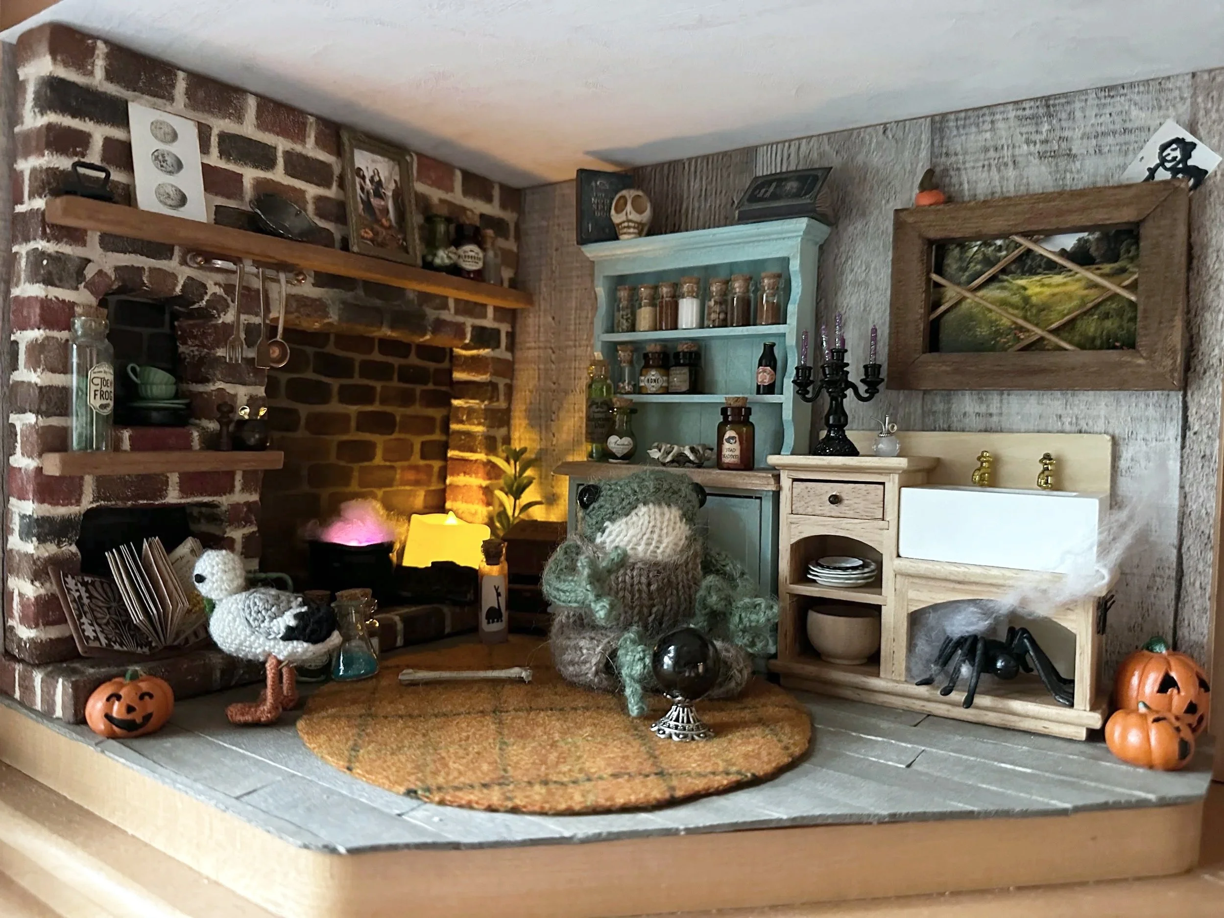Decorative kitchen shelf and countertop with Halloween decorations, pumpkins, a teddy bear, and various jars and bottles, against a brick and wood wall.