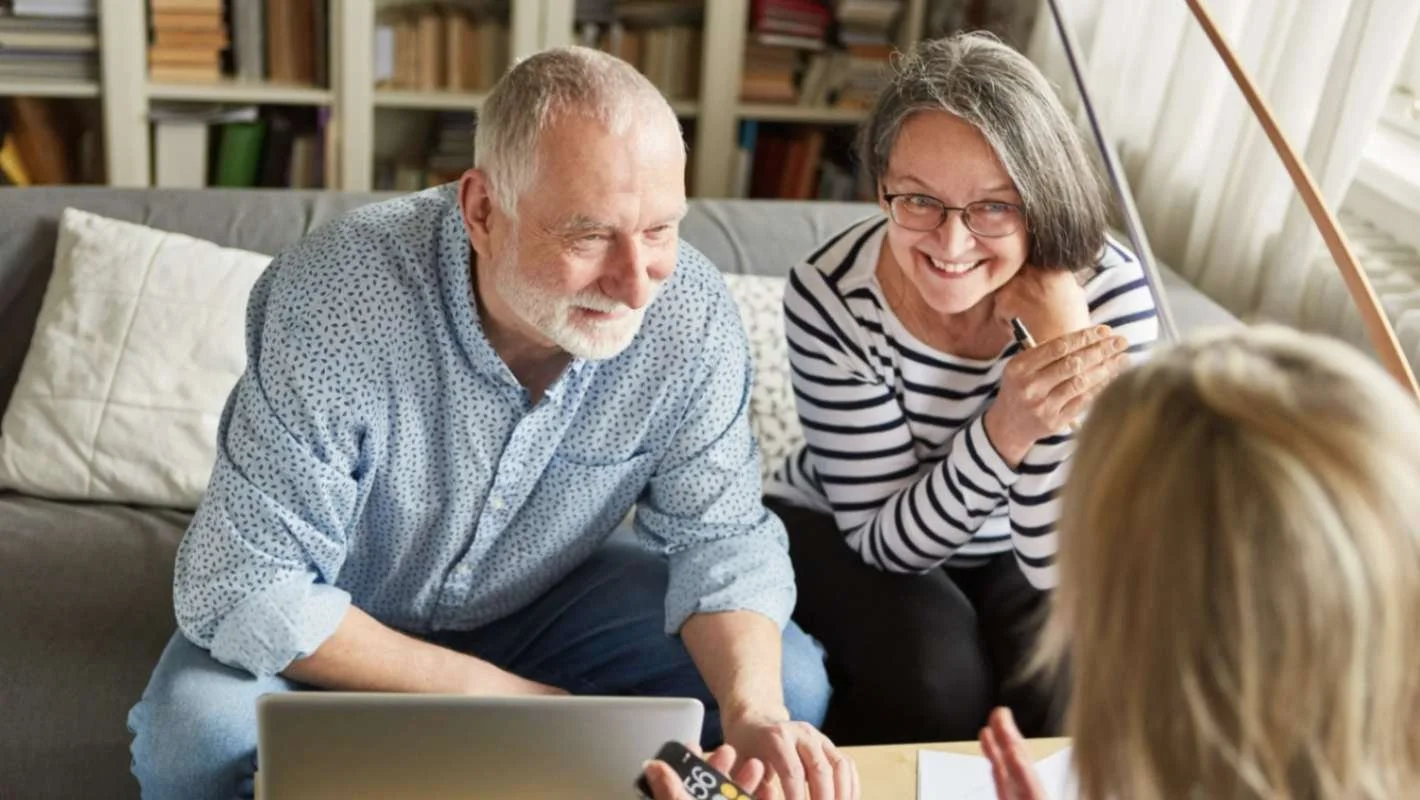 Senior couple receiving home care consultation and healthcare guidance from a caregiver during a home visit.