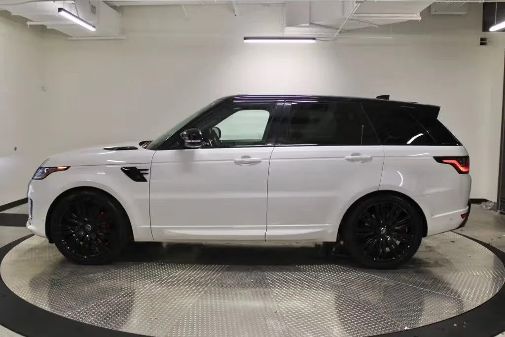 White SUV with black wheels and accents parked indoors, possibly a showroom or garage.