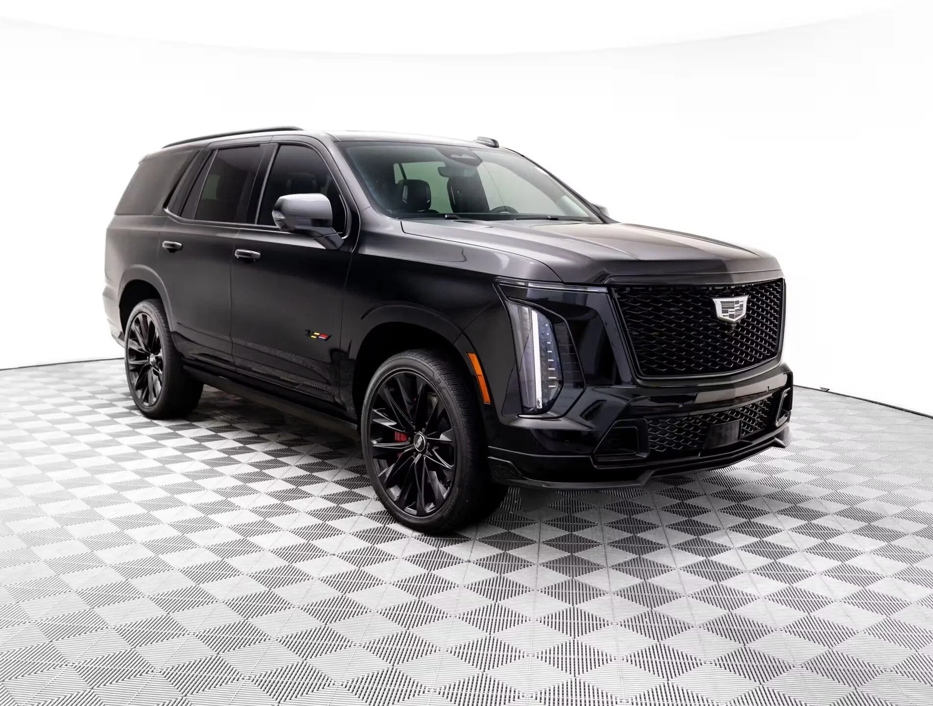 Black Cadillac SUV parked on a checkered floor against a plain white background.