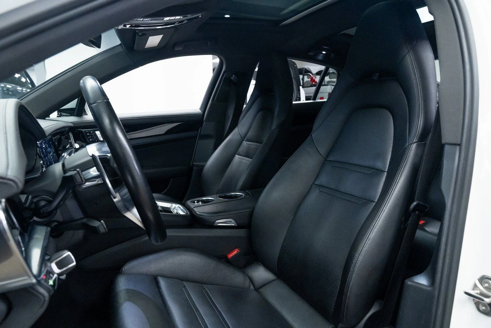 Interior of a modern luxury car showing black leather front seats, steering wheel, dashboard, and center console.