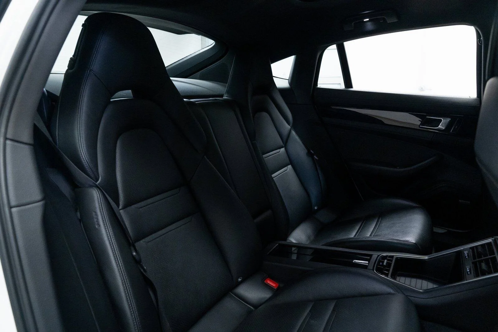 Interior of a car showing black leather seats, front and back, with door panels and window views.