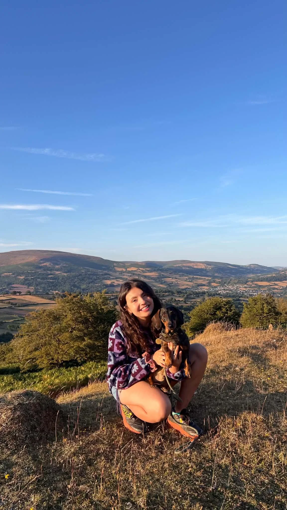 Woman holding a small dog in pretty landscape