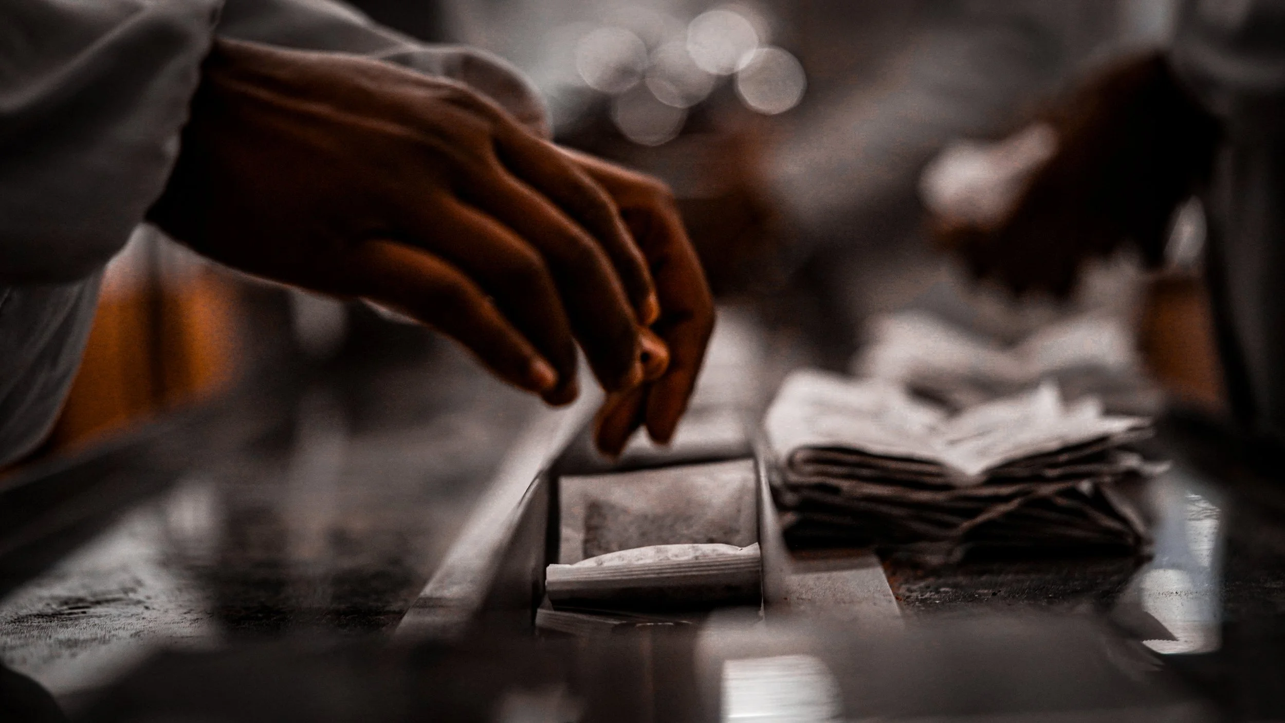 Close-up of a person's hand flipping through pages of newspapers on a table.