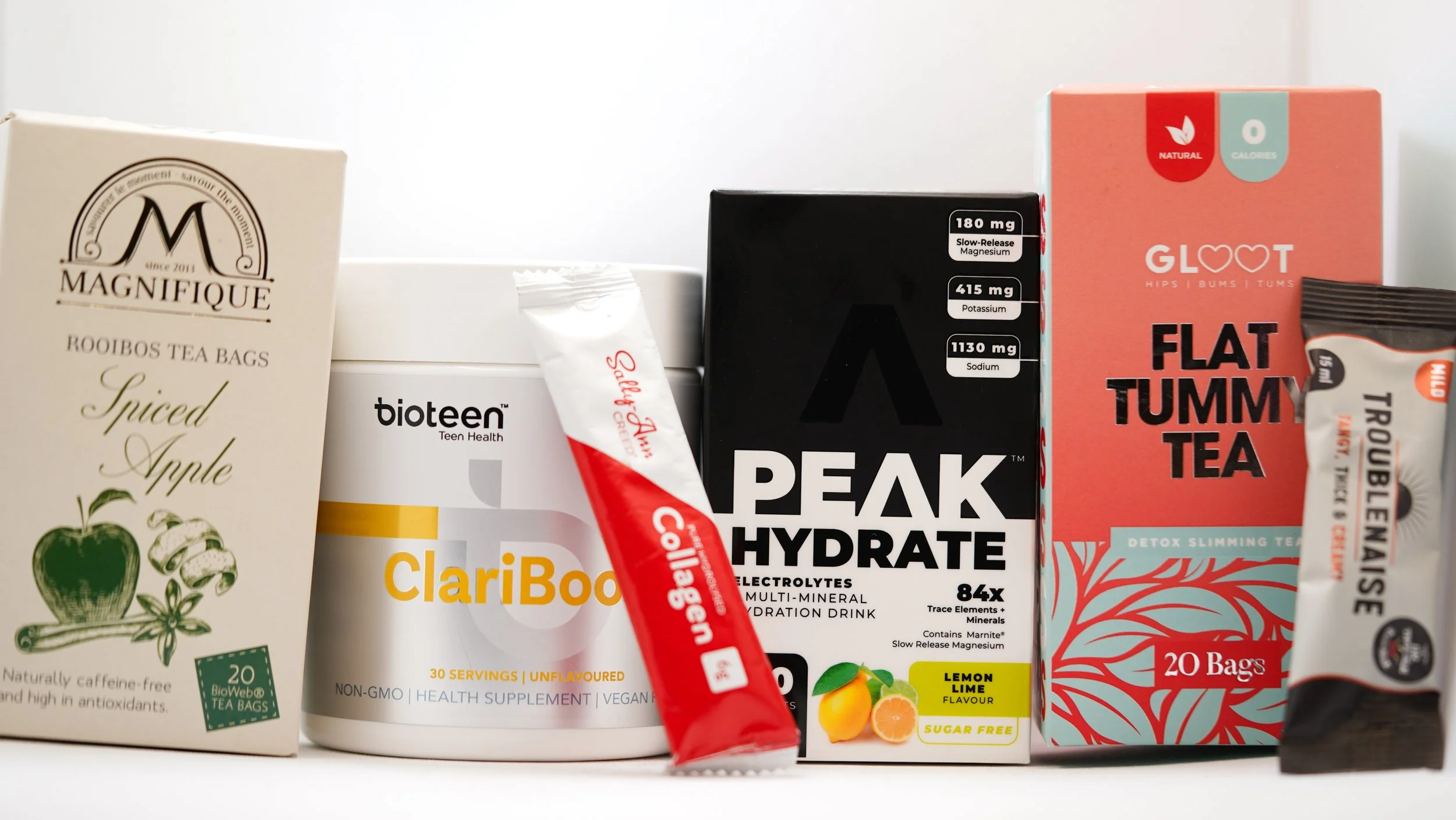 Collection of health and wellness products including tea bags, electrolyte powder, dietary supplements, and detox tea boxes.