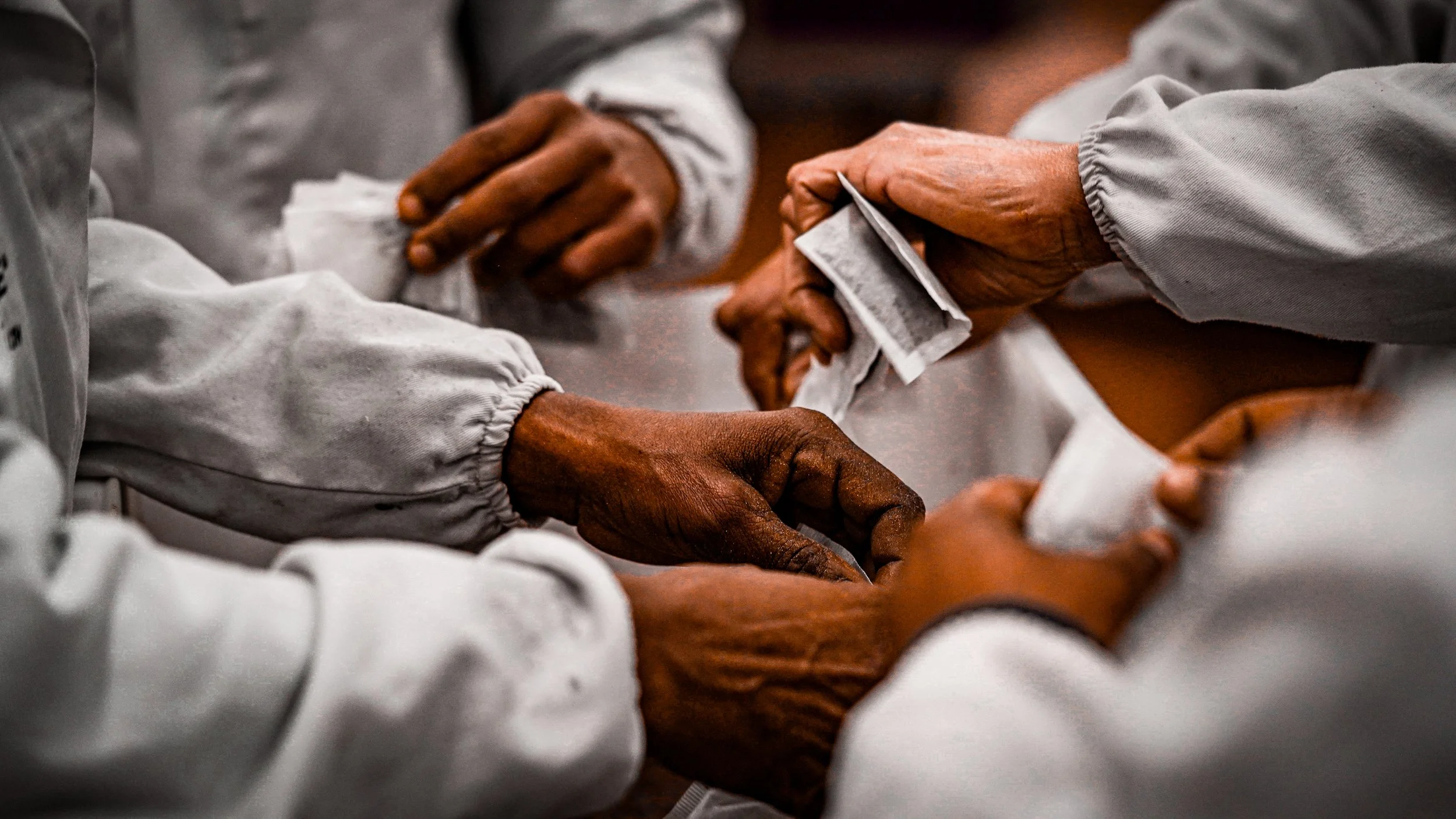 Close-up of hands exchanging money, with people wearing white attire.