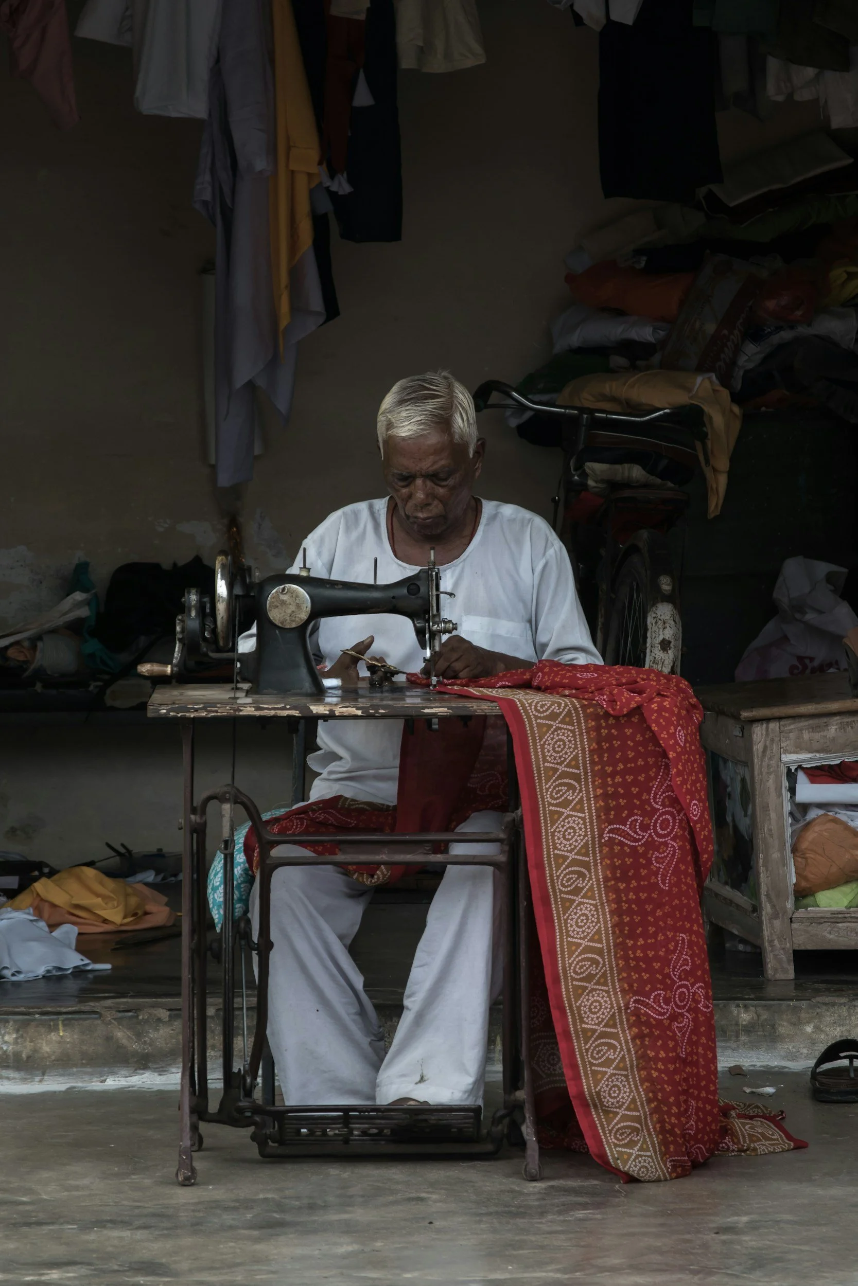 Indian artisan sewing fabric in his workshop