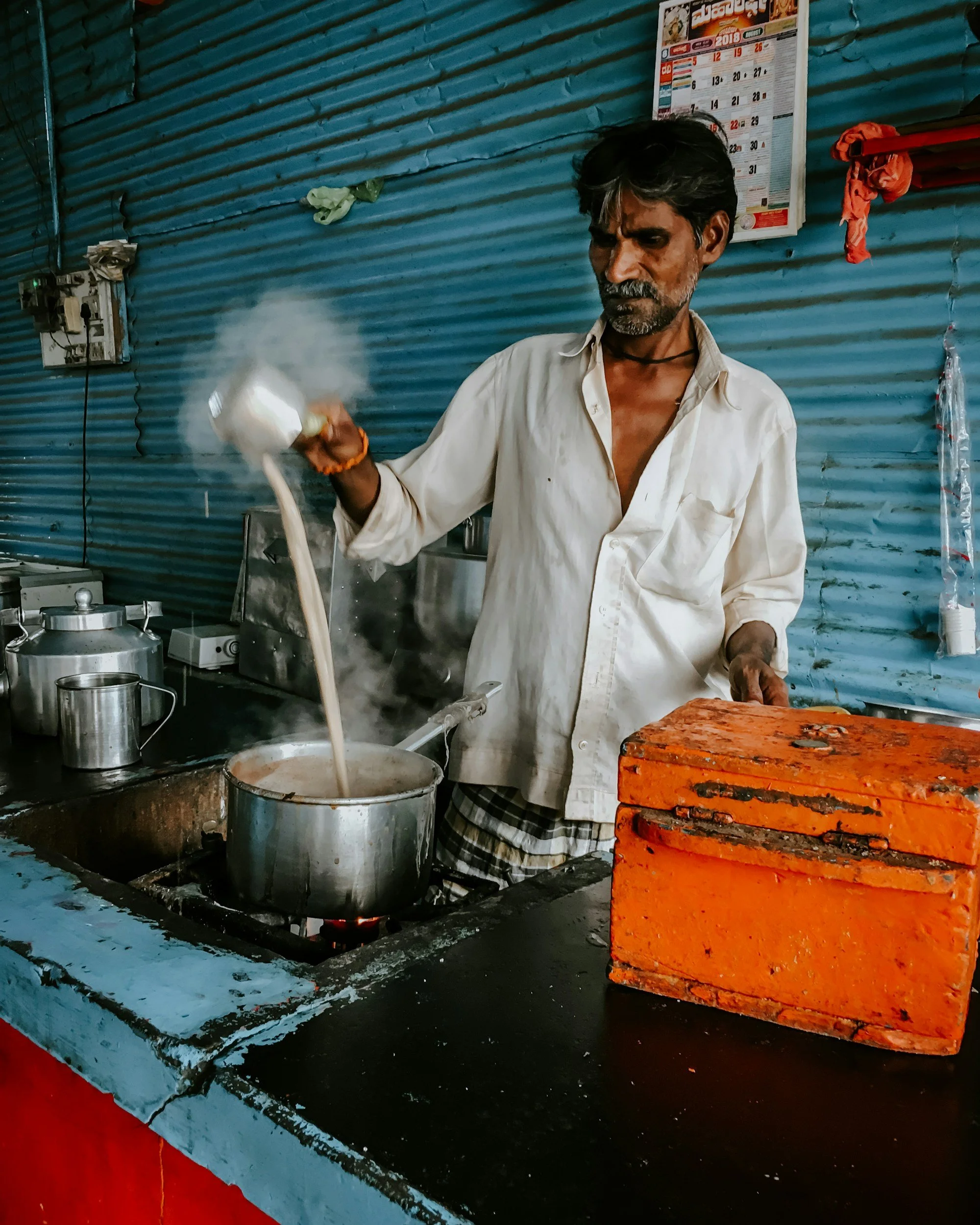 Chaiwala pouring steaming tea at a roadside stall in India