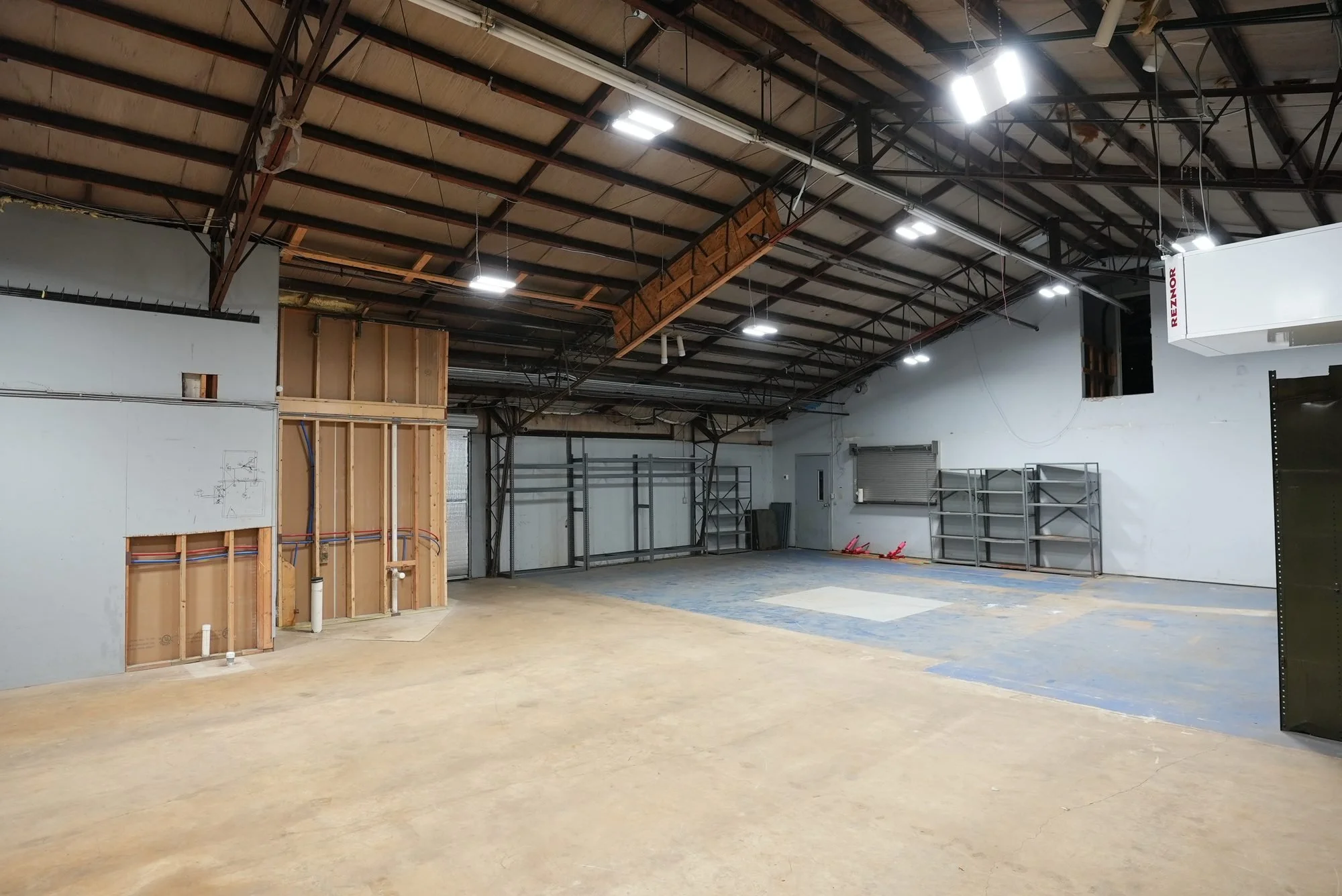 Empty interior space under construction with partially finished walls and exposed ceiling beams.