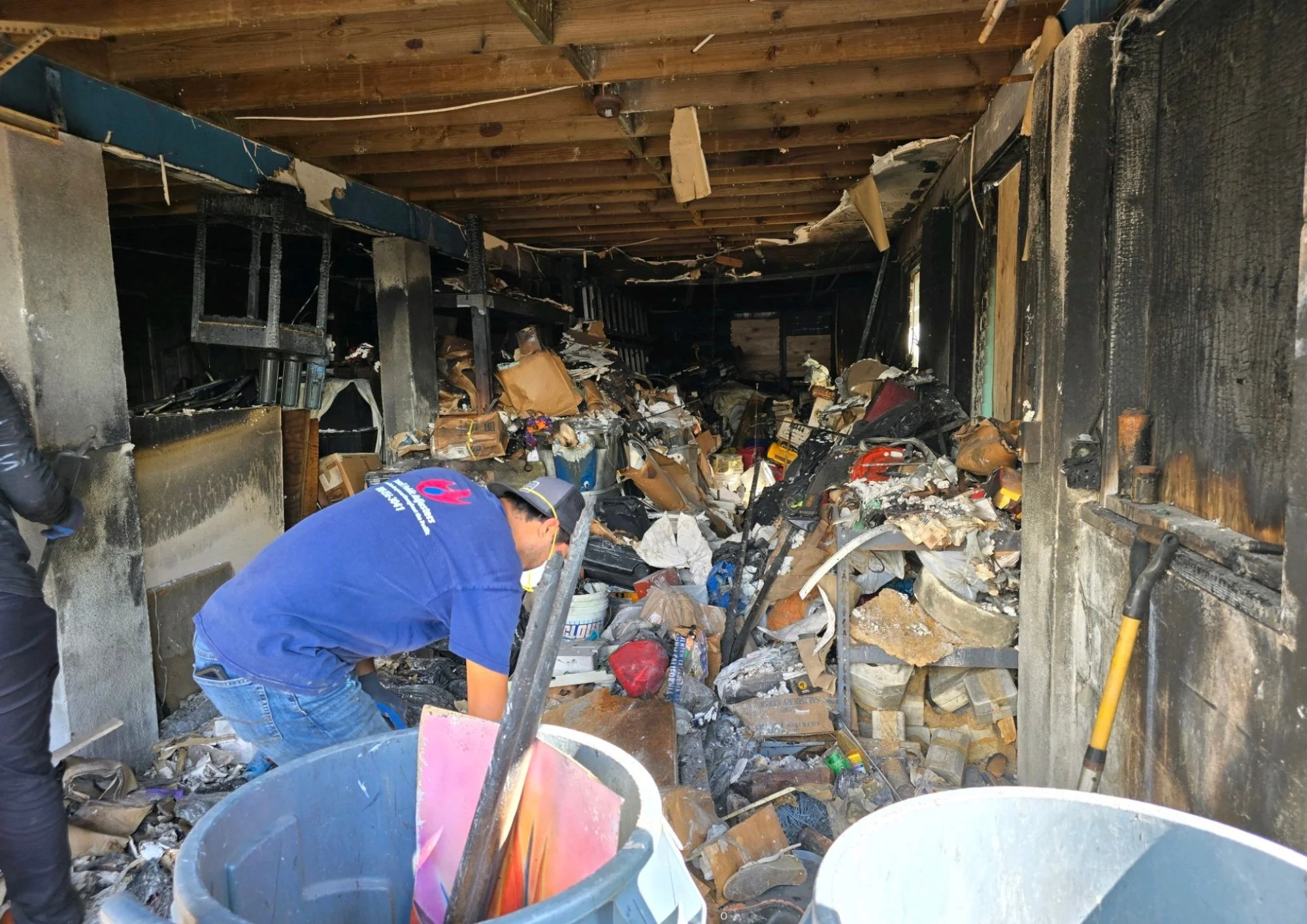 Person working inside a burned and damaged building with charred walls and debris.