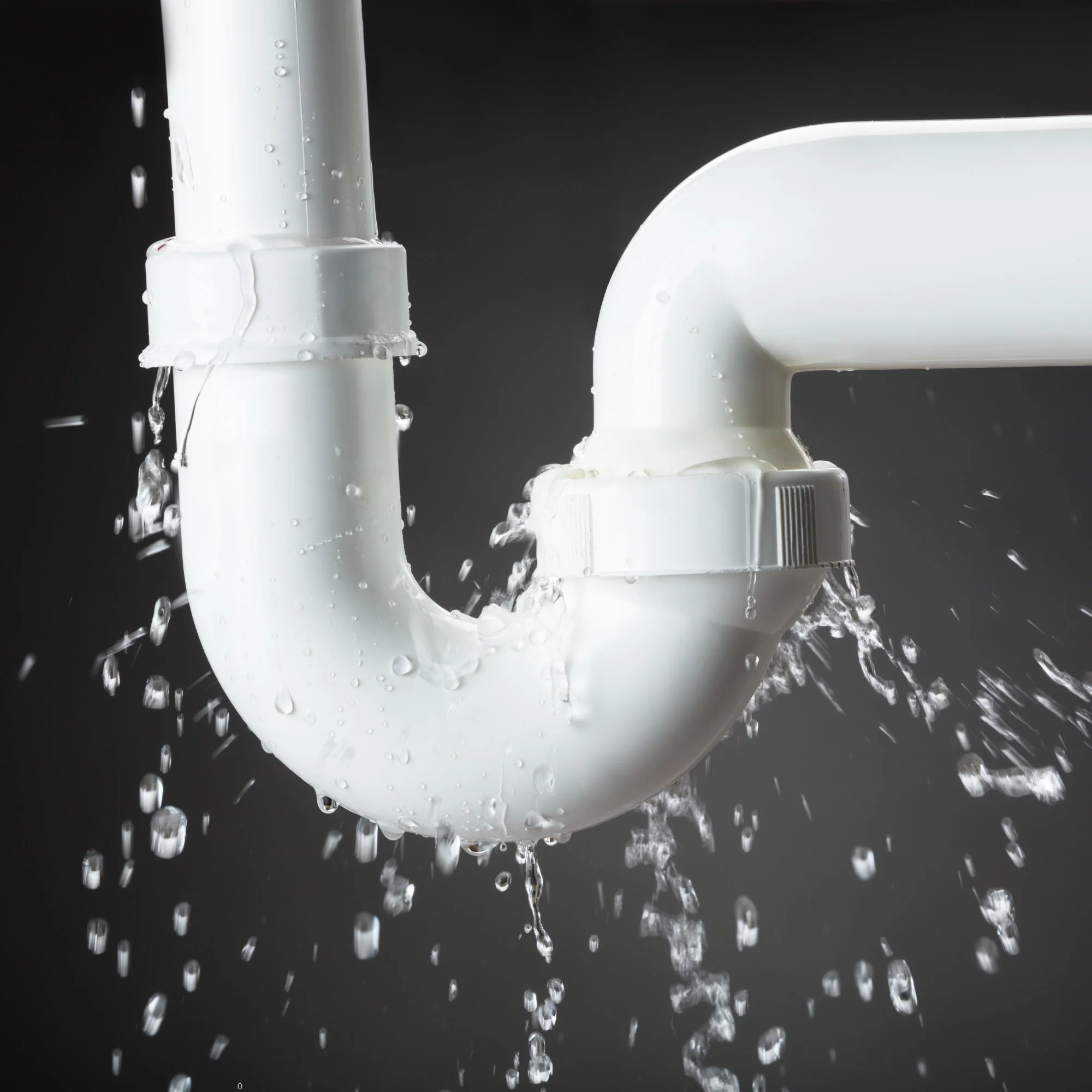 Close-up of white PVC pipes with water droplets, with a dark background.