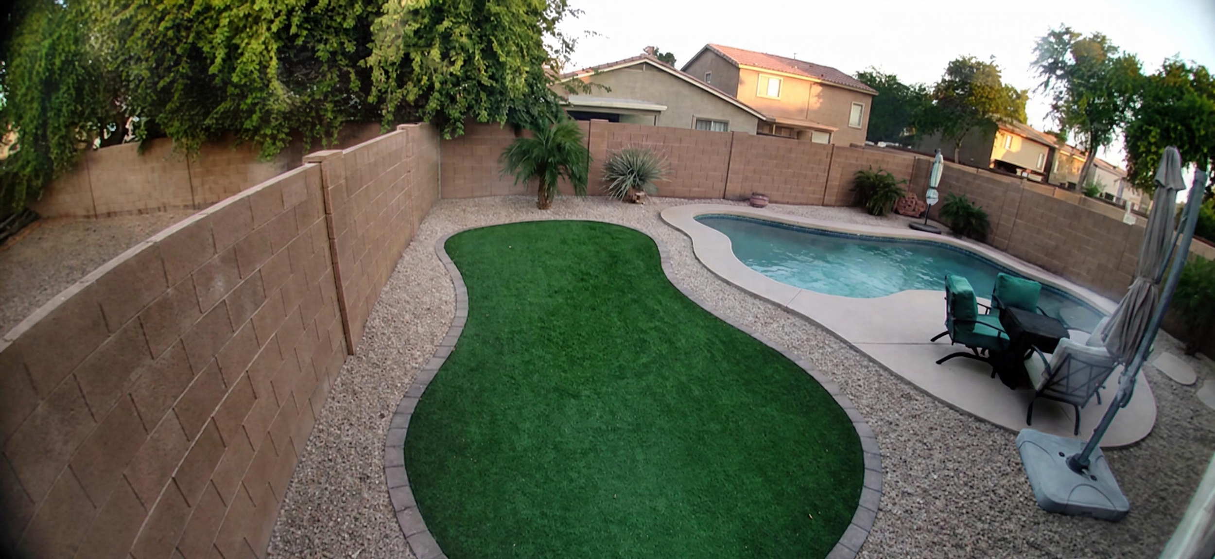 Picture of Backyard with Artificial Turf, Rock, and Pool to illustrate areas beyond the Artificial Turf such as rock that may need deodorizing treatment for odors from pet use.