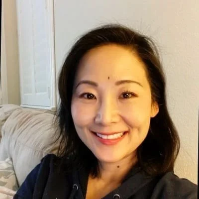 A woman smiling and posing for a selfie in a home setting.