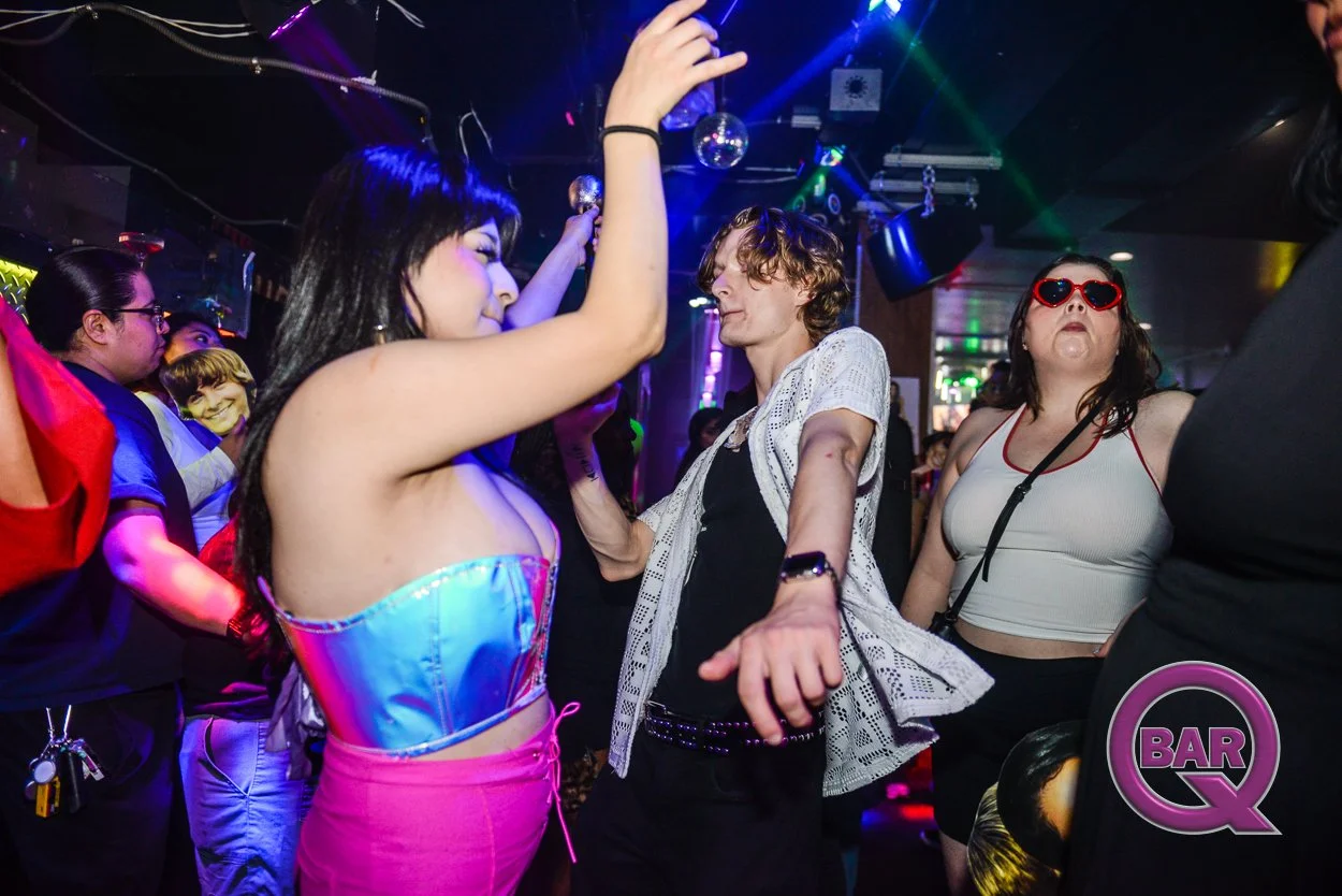 People dancing and enjoying music at a nightclub with colorful lights.