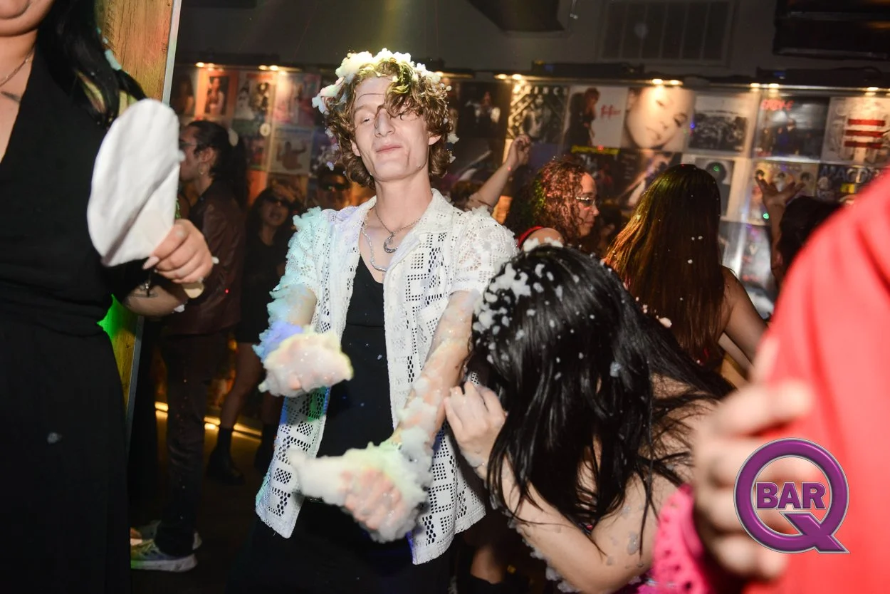 People dancing and having fun at a party or nightclub with foam or soap pouring over them.