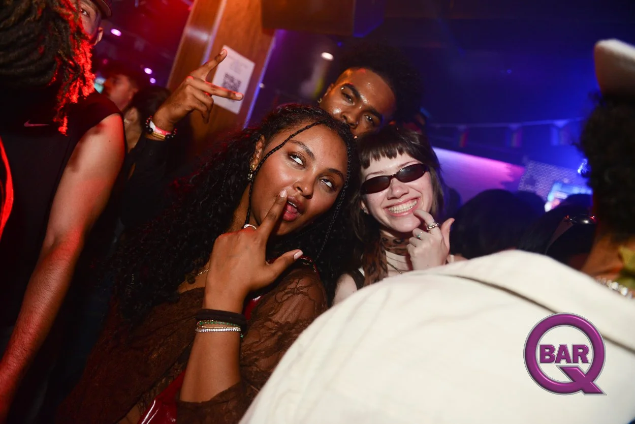 A group of friends enjoying themselves at a nightclub with colorful lighting, smiling, and making playful gestures.