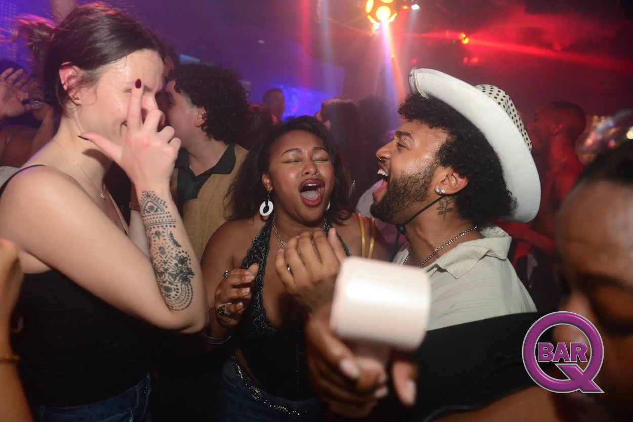 Group of friends dancing and singing together in a nightclub, with colorful lights and a lively atmosphere.