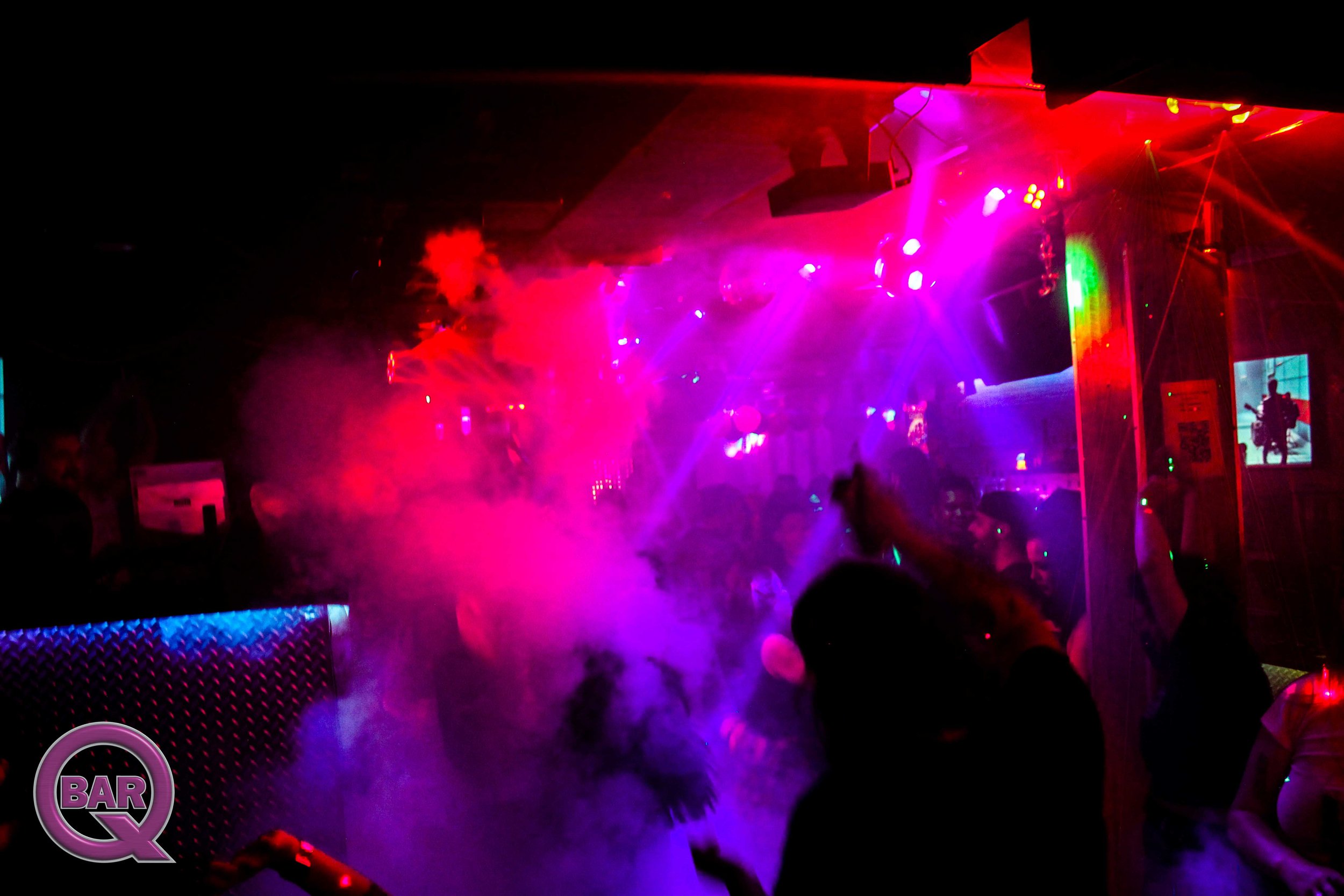 Concert scene with colorful lights, smoke, and silhouettes of people dancing.