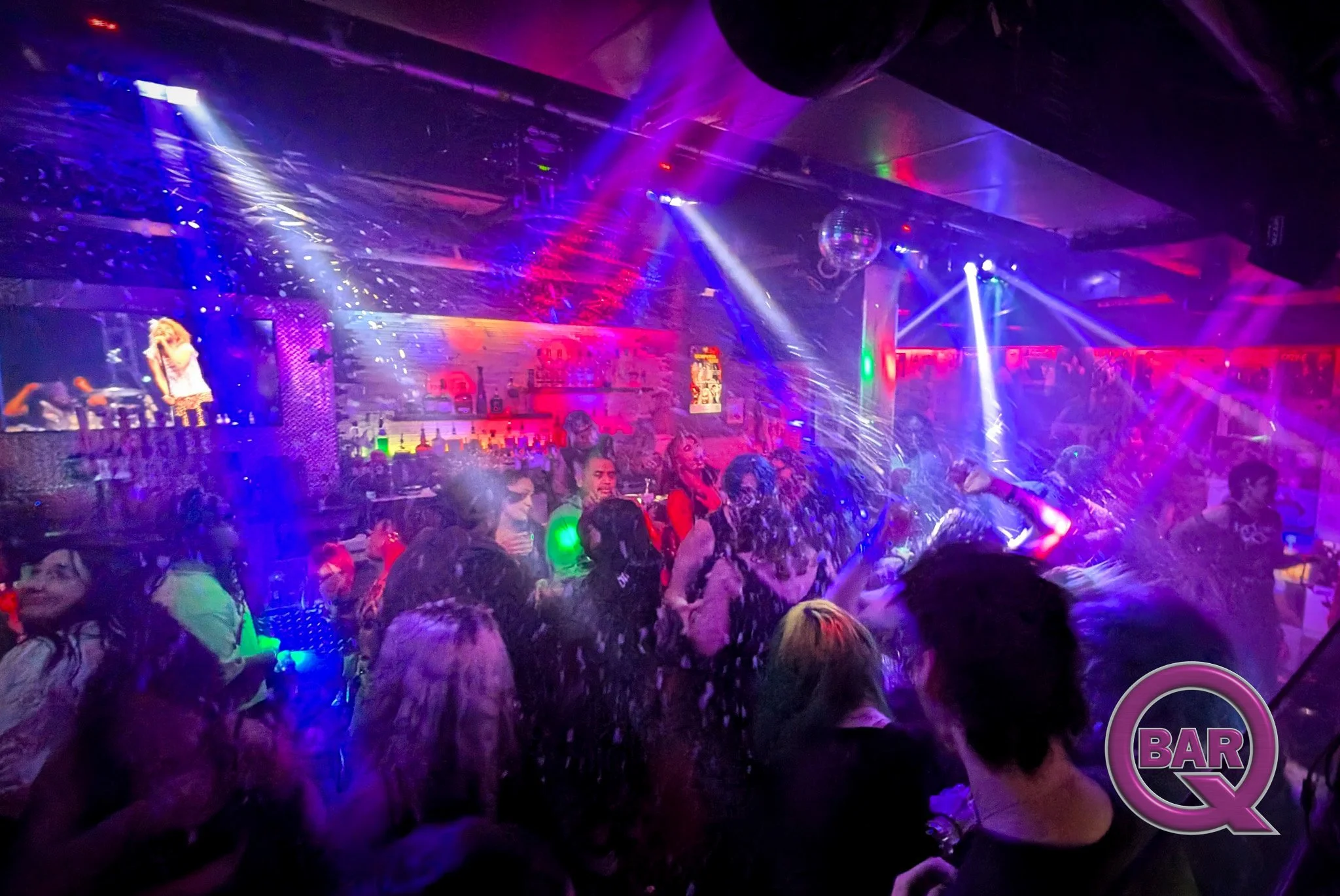 Crowded nightclub with colorful lighting, a singer on stage, and dancing people.