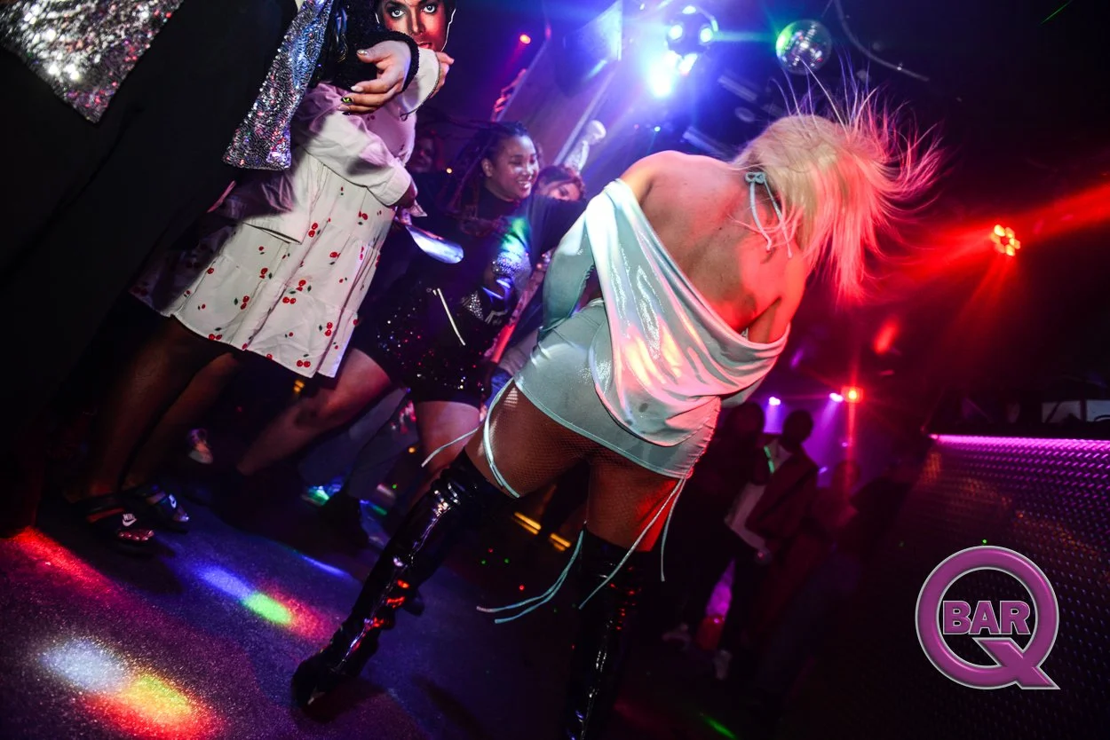 A woman dancing in a club with colorful lights and other partygoers watching.