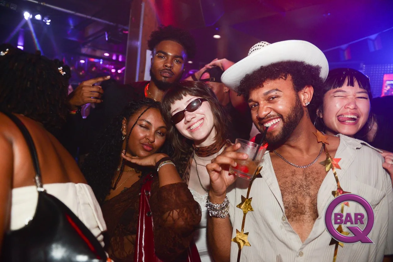 Group of diverse young adults dancing and having fun at a nightclub with colorful lighting.