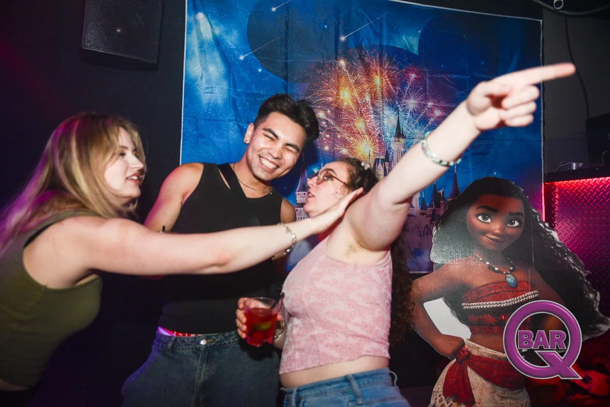 Group of friends having fun and sharing a high-five in a nightclub with festive fireworks and decorations in the background.