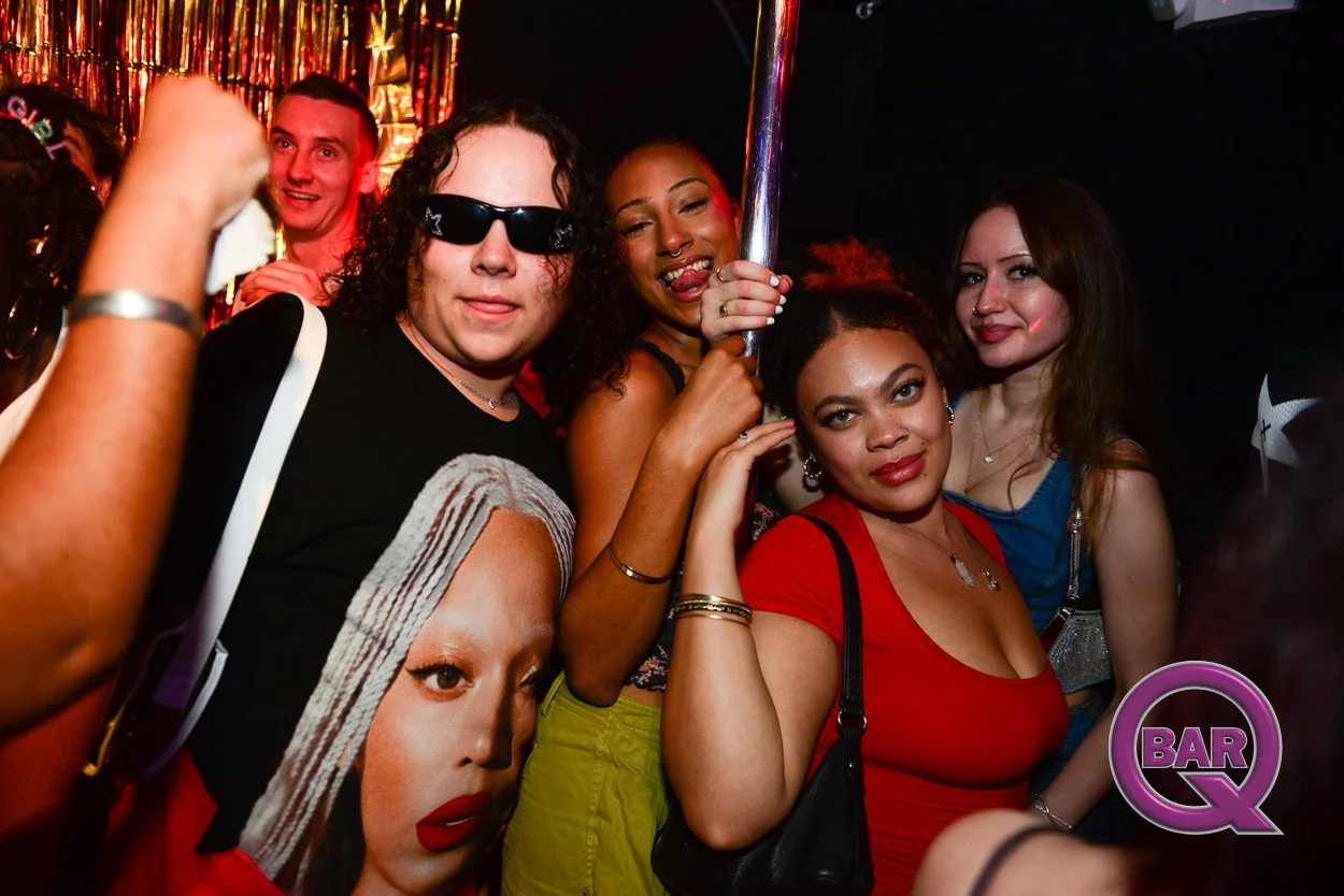 Group of five diverse women and one man enjoying a night out at a bar or nightclub, with colorful lighting and a party atmosphere.