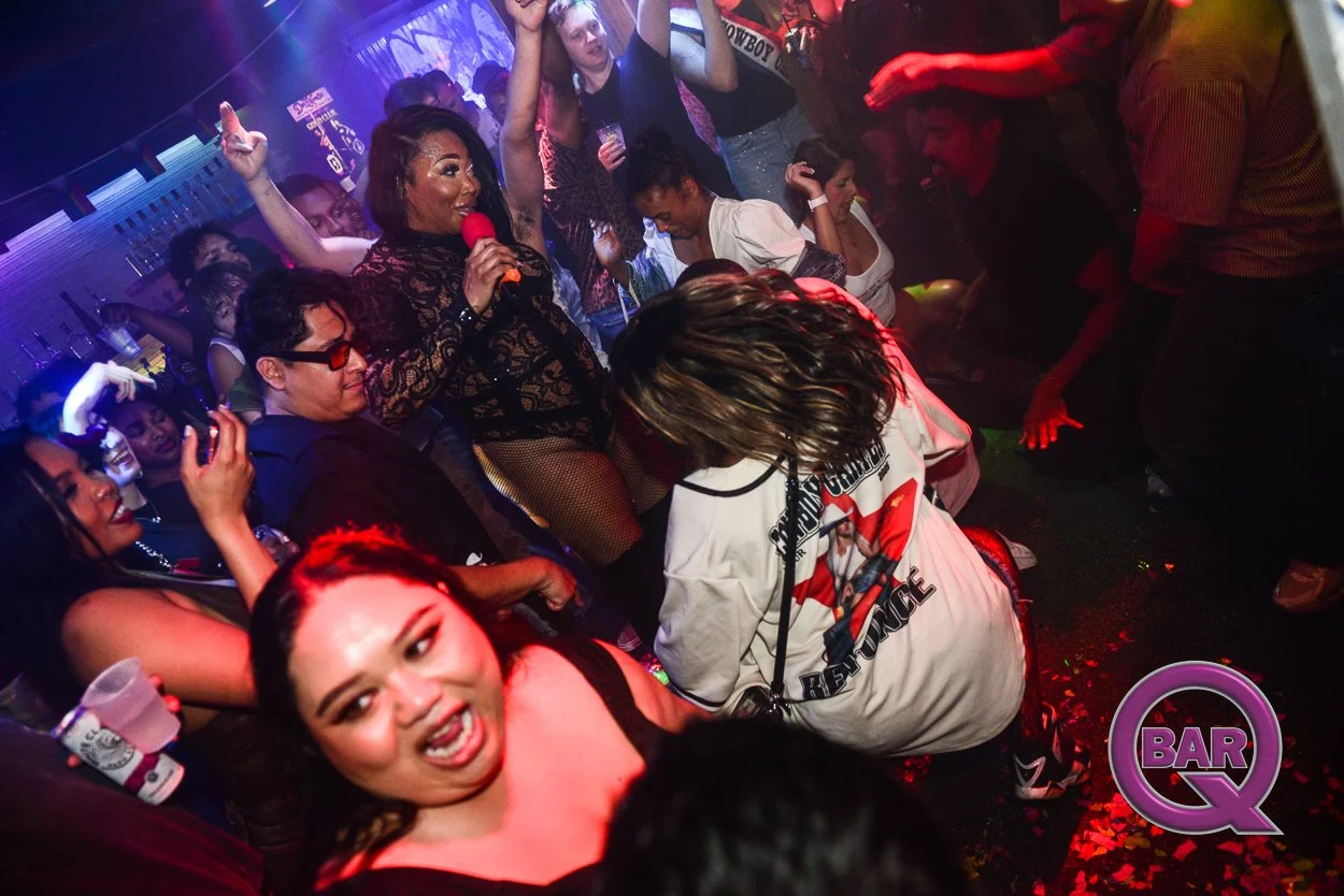People dancing and singing at a nightclub with colorful lighting and a woman holding a microphone.