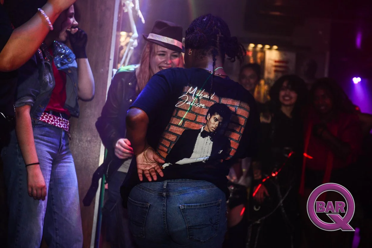 Group of people dancing and enjoying themselves in a nightclub with colorful lighting.