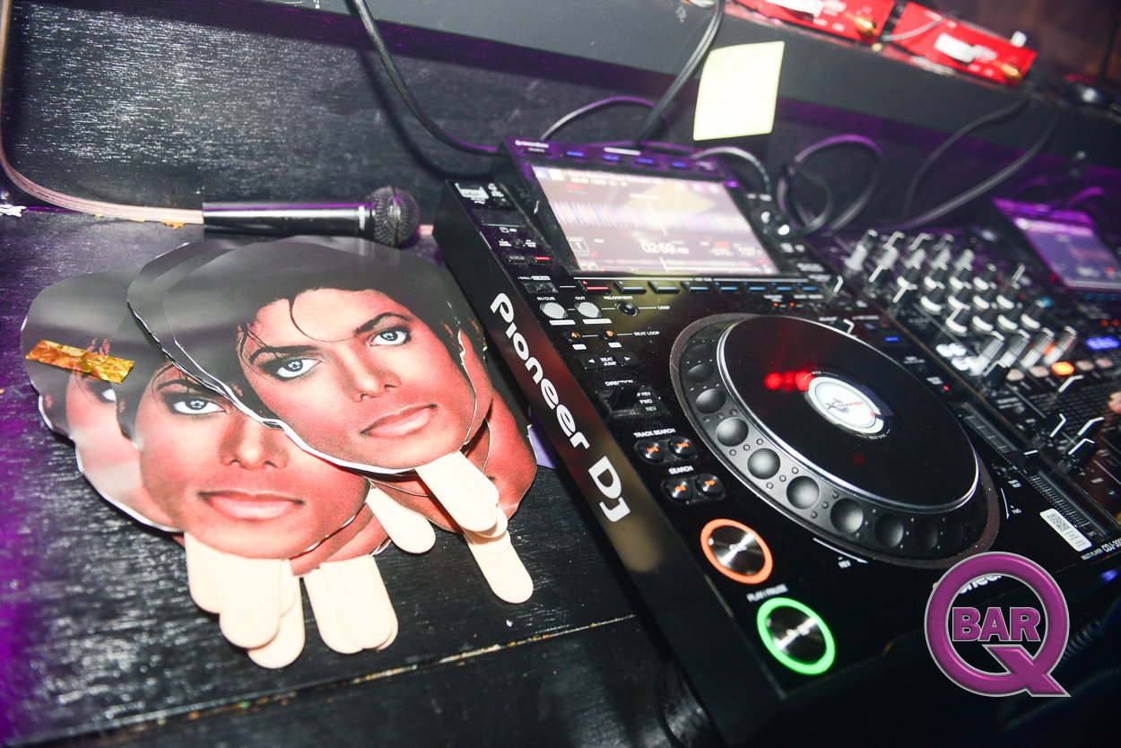 DJ equipment including a Pioneer DJ controller, a microphone, and several pictures of Michael Jackson on the table.
