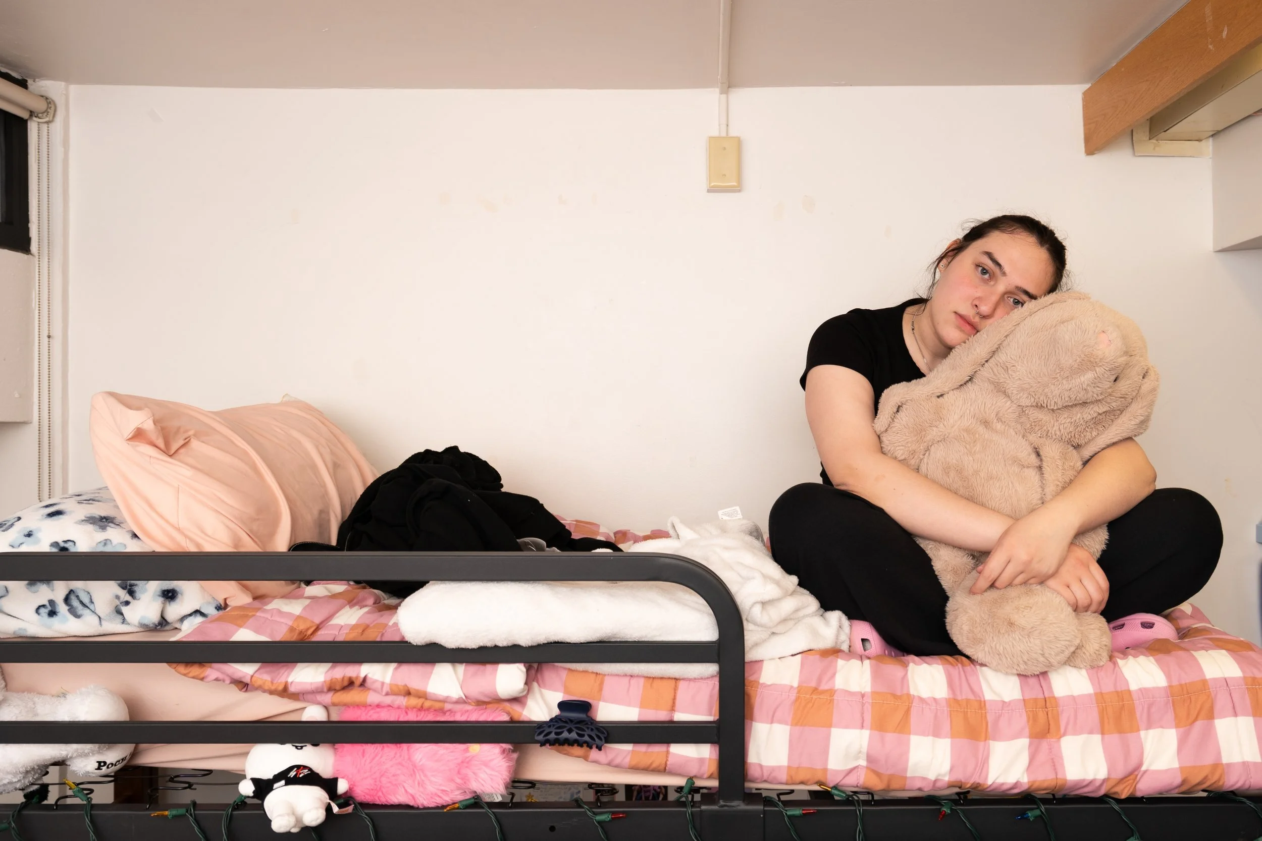 Madi Gentes poses for a portrait on her bed in her college dorm room while holding her stuffed rabbit at Rochester Institute of Technology on Apr. 20, 2025 in Rochester, N.Y. Alicia has a white stuffed rabbit to match Madi that they bought together.