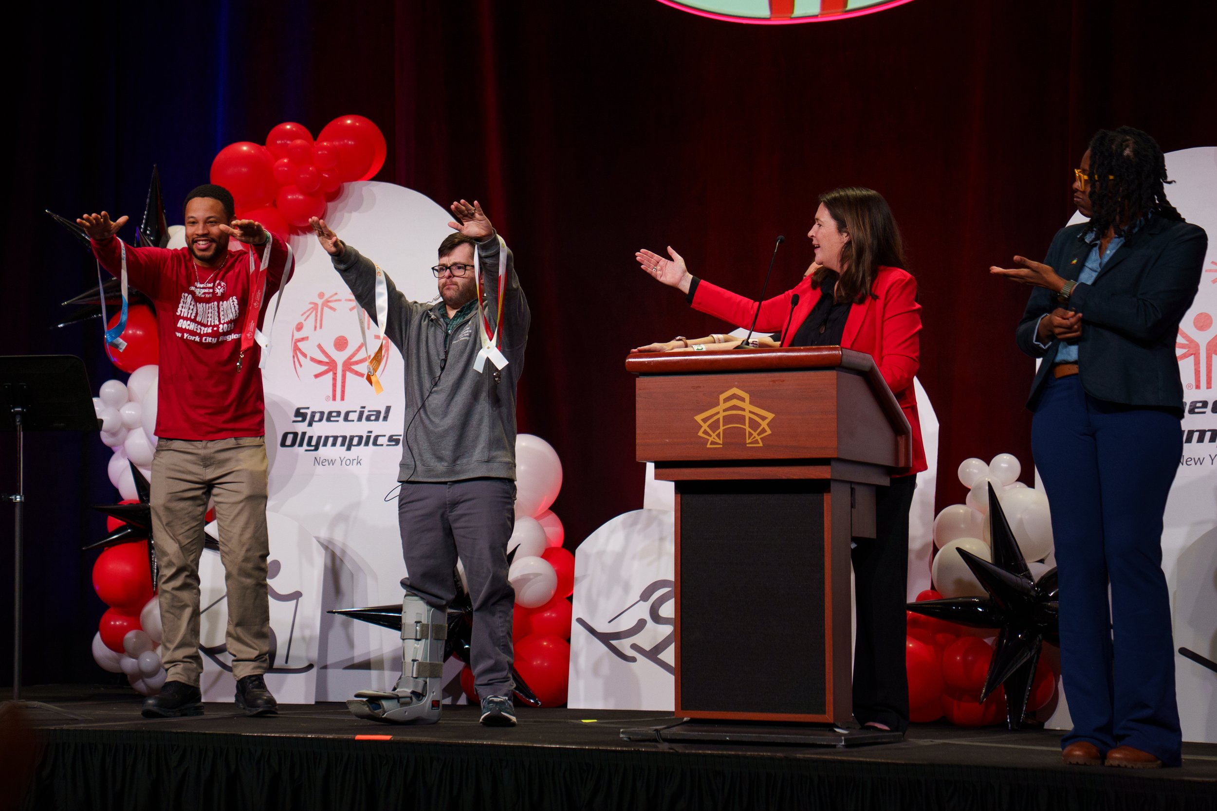 Special Olympics New York President Stacey Hengsterman gestures to Jude Killar as he shows off the new medals during the opening ceremonies at Joseph A. Floreano Rochester Riverside Convention Center in Rochester, N.Y. on Feb. 20, 2026.