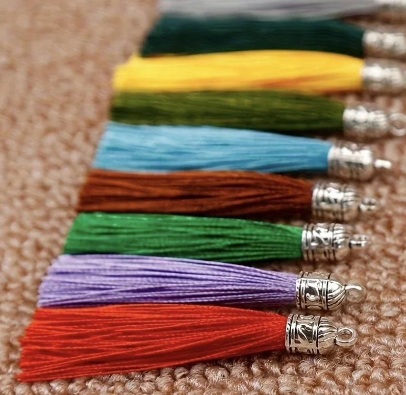 Varios llaveros de borla de colores alineados sobre una superficie de tela. 