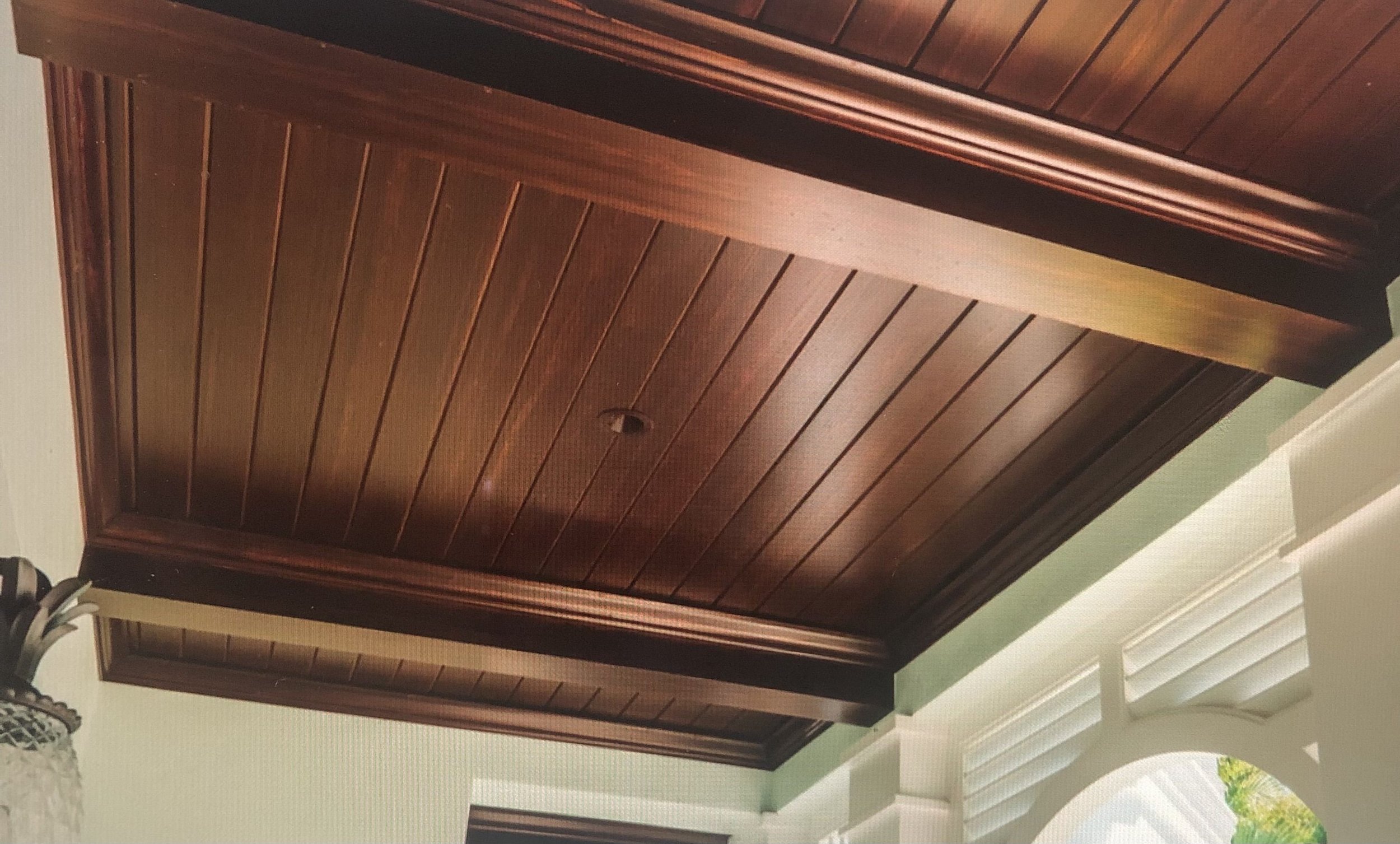 Wooden cabinet door with horizontal panels and a decorative trim at the top, set in a room with green walls and white trim.