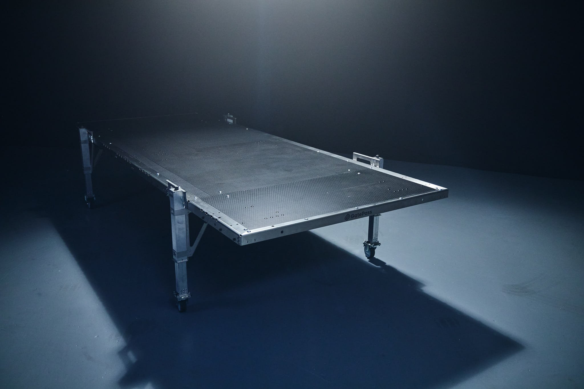 A metal platform with legs in a dark room, with the brand name 'GatePass' visible on the side of the platform.