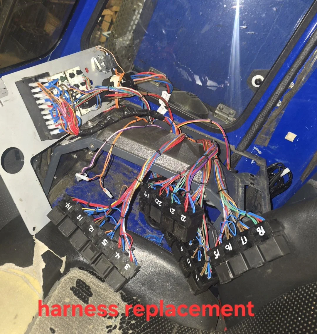 Interior view of a vehicle with exposed wiring and fuse box, indicating harness replacement work.