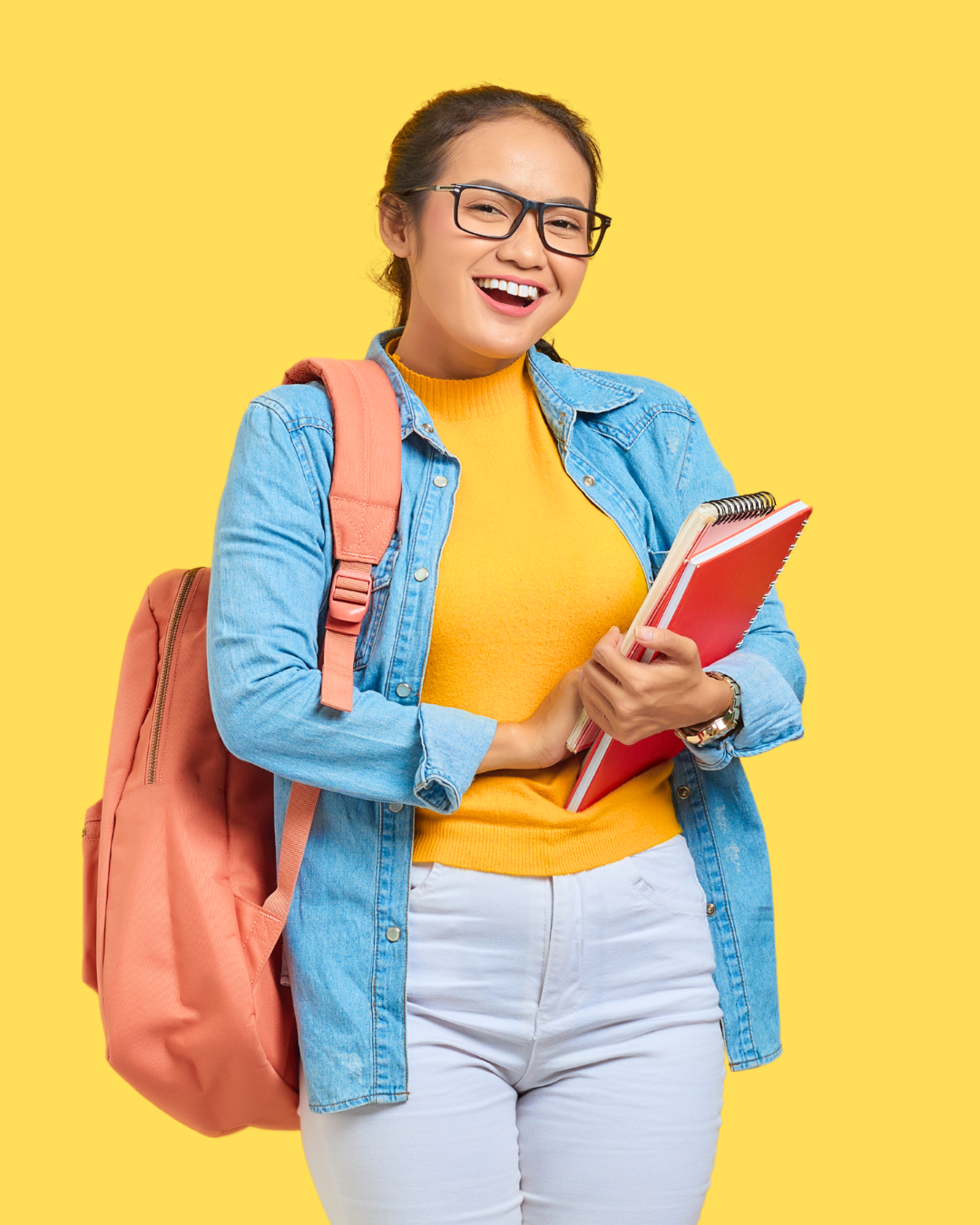 A young woman smiling, wearing glasses, a denim jacket over a yellow sweater, carrying a pink backpack, holding notebooks, standing against a yellow background.