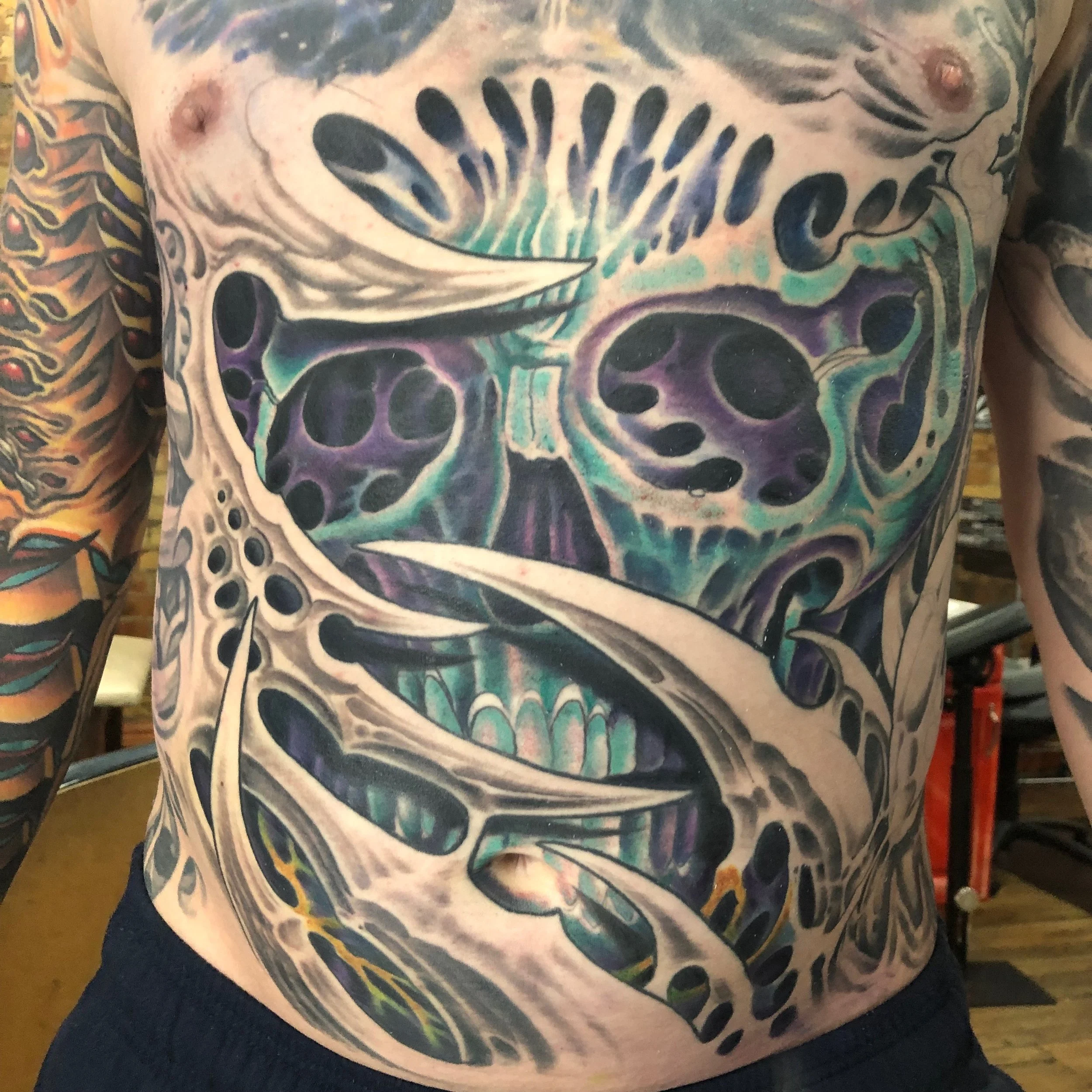 Close-up of a person's chest with a large, colorful tattoo of a butterfly with intricate black, purple, and teal patterns.