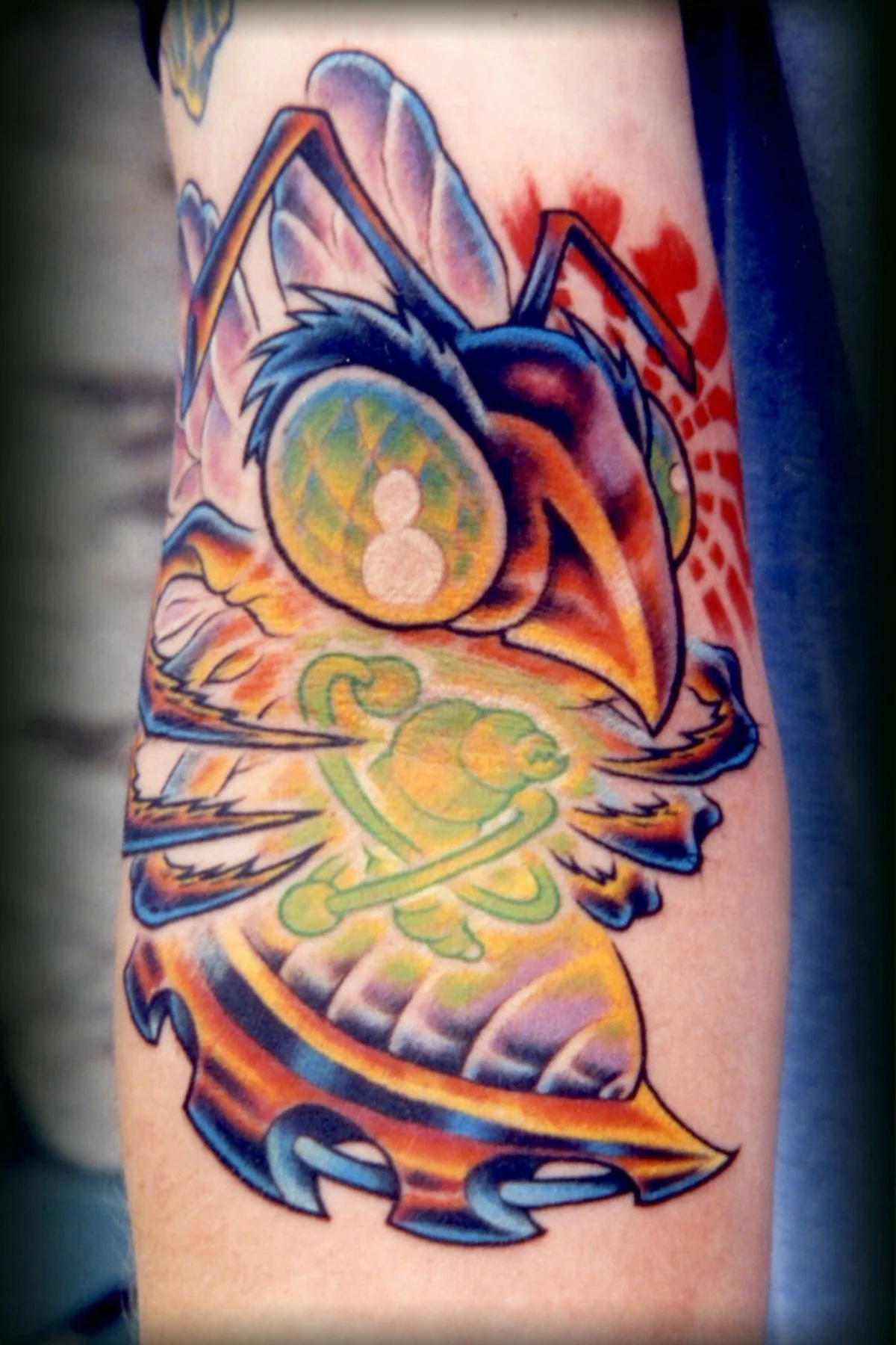 Colorful tattoo of a meditative frog with headphones, surrounded by abstract and vibrant background designs.