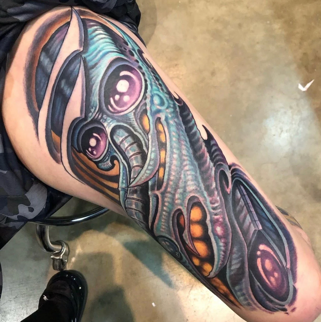 Colorful tattoo of a stylized octopus on a person's thigh.
