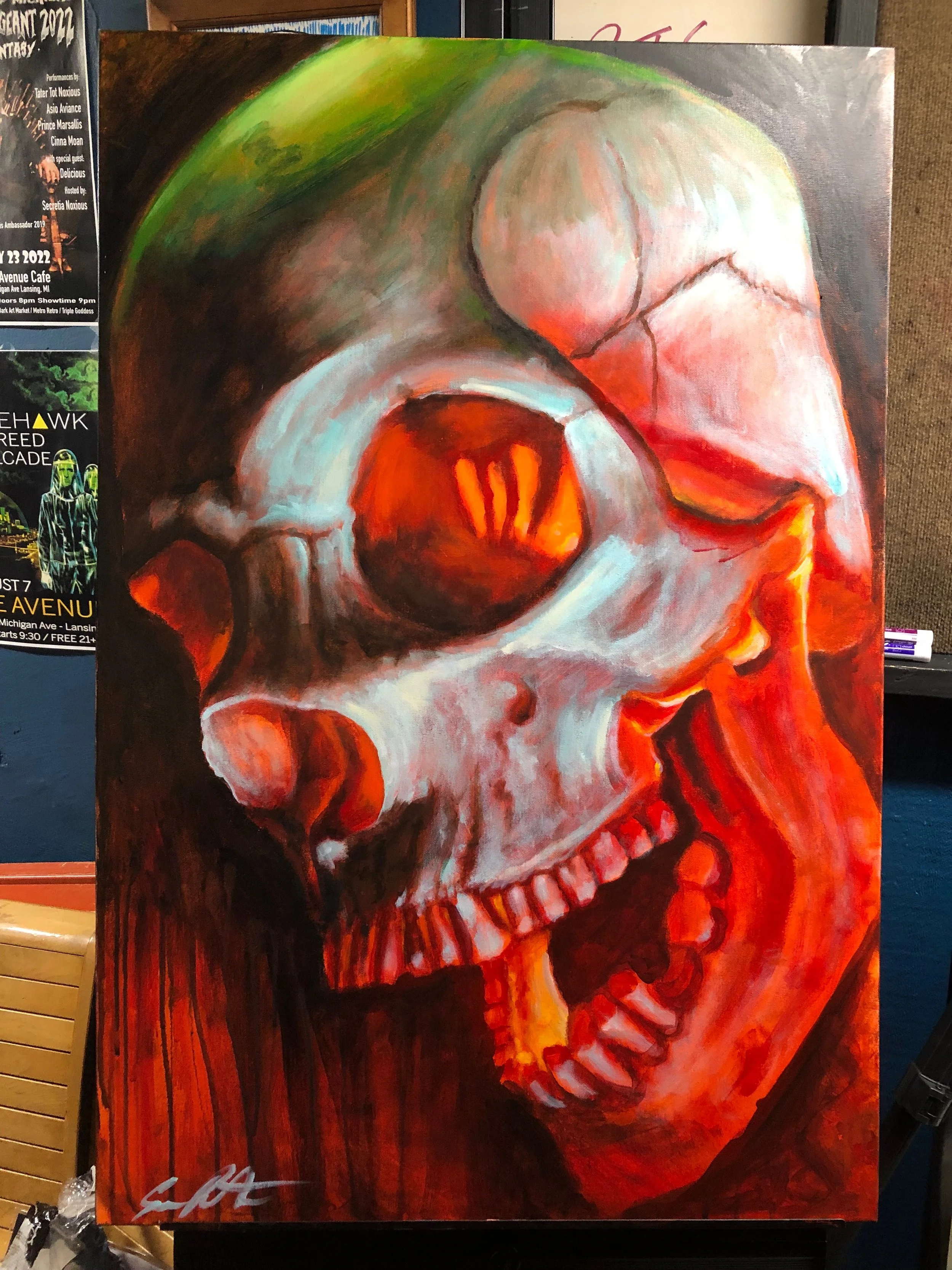 A painting of a human skull with an exaggerated, stylized look. The skull features prominent eye sockets, nose cavity, and teeth, with vibrant colors of red, orange, white, green, and black, creating a striking and intense visual effect.
